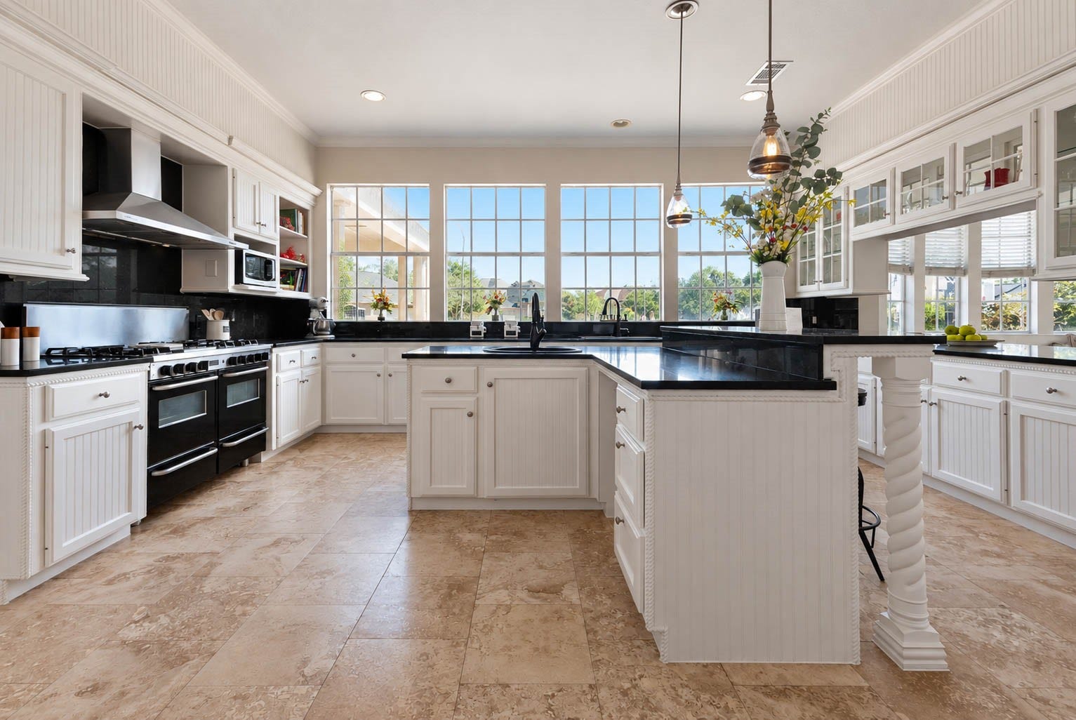 33103 Whickham Circle, Fulshear, TX 77441 This beautiful kitchen is anchored by a large, centrally positioned island offering generous prep space, a separate sink, & abundant storage. An elevated breakfast bar overlooks the island, while pendant lighting adds warmth overhead. A dramatic wall of windows creates a stunning backdrop, filling the space with natural light.