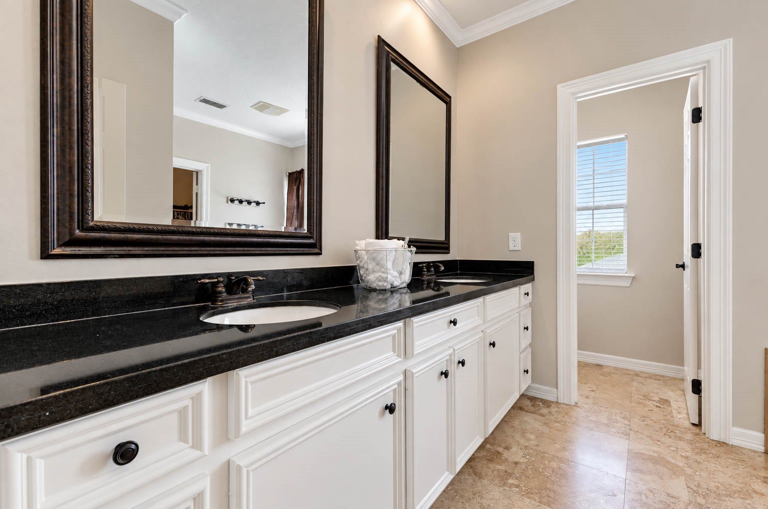 33103 Whickham Circle, Fulshear, TX 77441 The primary bath features an elongated granite-topped vanity with abundant cabinetry and oversized framed mirrors. High ceilings accented by crown molding enhance the spacious feel, while neutral tile flooring creates a polished, spa-inspired aesthetic. A private water closet is thoughtfully positioned beyond for added privacy.