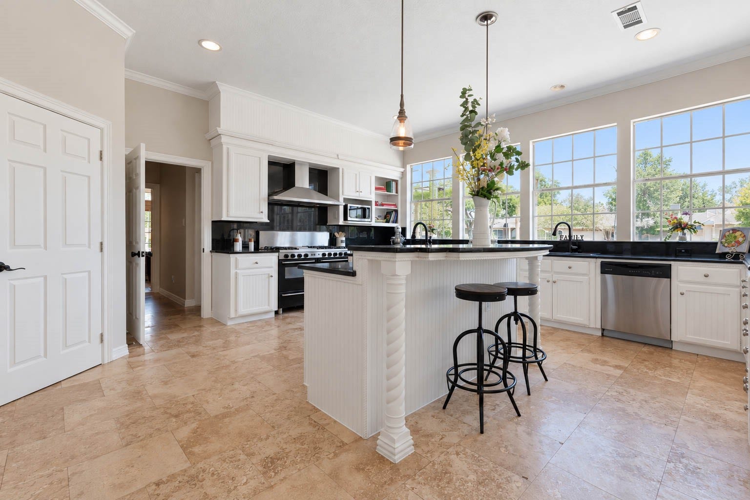 33103 Whickham Circle, Fulshear, TX 77441 This impressive kitchen pairs timeless white cabinetry with rich dark granite countertops, a coordinating backsplash, & a professional-style gas range with stainless vent hood. A generously sized island with a raised breakfast bar adds valuable prep and serving space while offering casual seating for everyday gatherings.