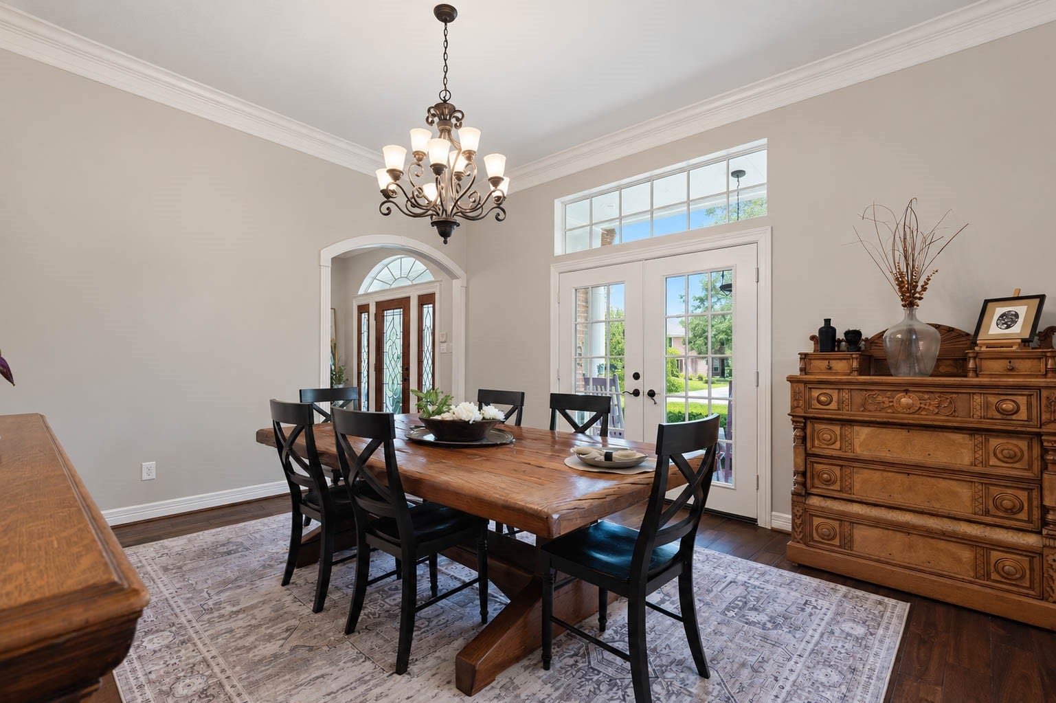 33103 Whickham Circle, Fulshear, TX 77441 A second perspective of the formal dining room highlights its substantial scale, hardwood flooring, crown molding, and elegant chandelier. Tall windows and architectural openings introduce natural light while adding depth and character to the space.