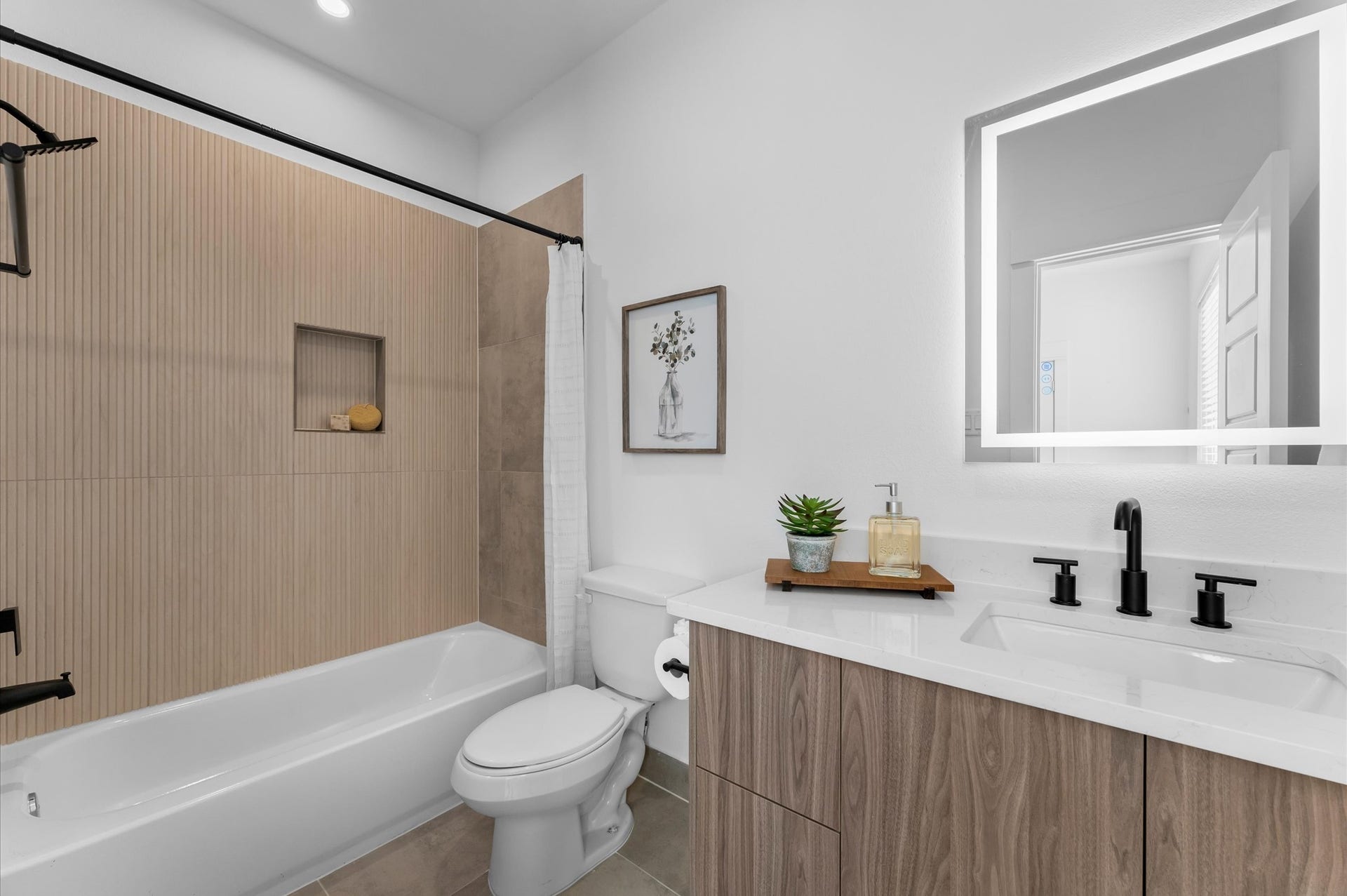 This ensuite bathroom, located in the third-floor secondary bedroom, showcases sleek modern finishes with stylish tile, a contemporary vanity topped with quartz countertops, and elegant lighting that brightens the space, creating a private retreat that is both functional and sophisticated.