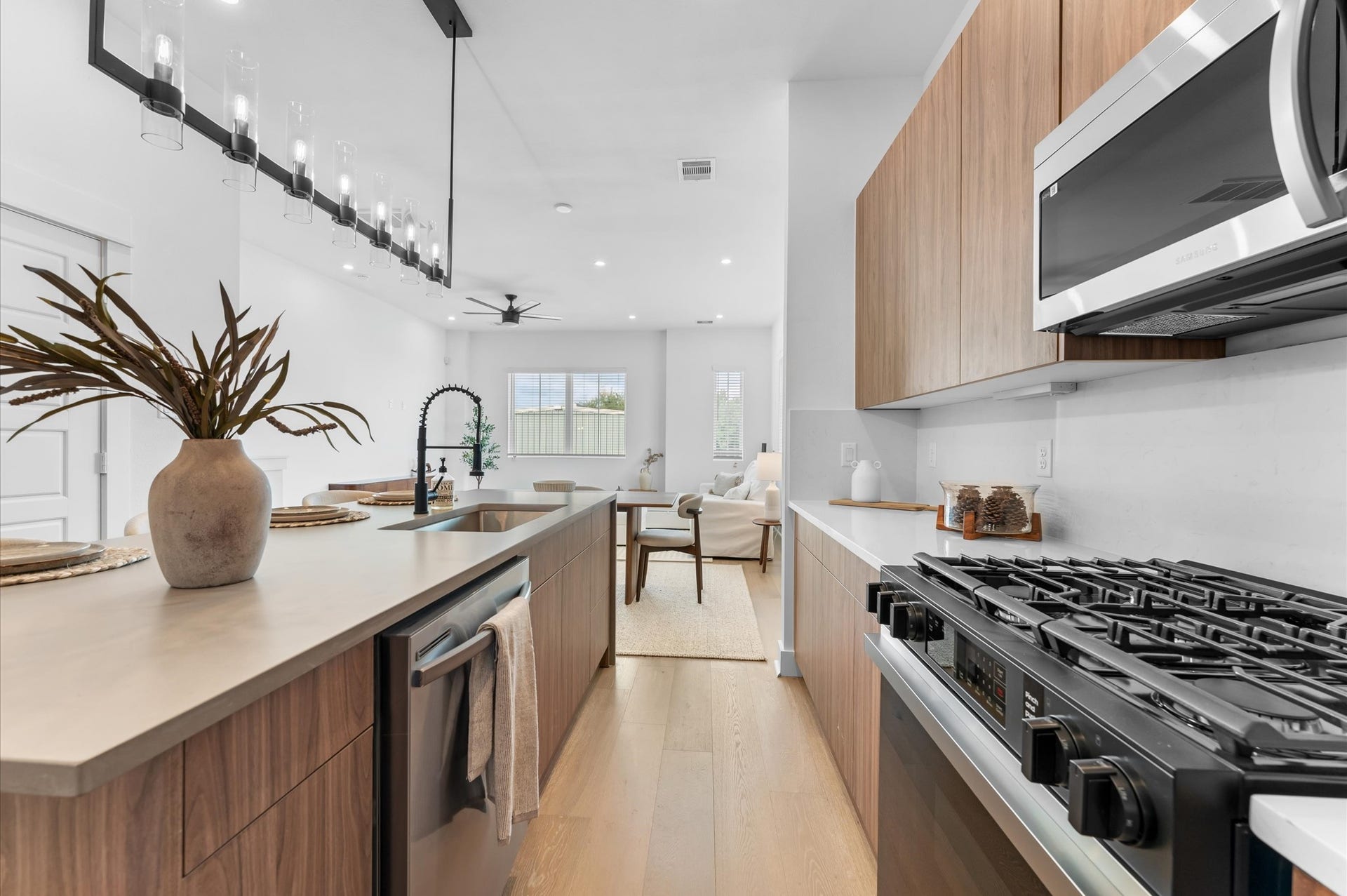 The kitchen, the heart of the second-floor open-concept living, dining, and kitchen, features a spacious island with a one-sided cascade quartz countertop, farmhouse sink, and modern pendant lights, complemented by an abundance of sleek, modern cabinetry providing ample storage, perfect for meal prep, casual breakfasts, or gathering with family and friends.