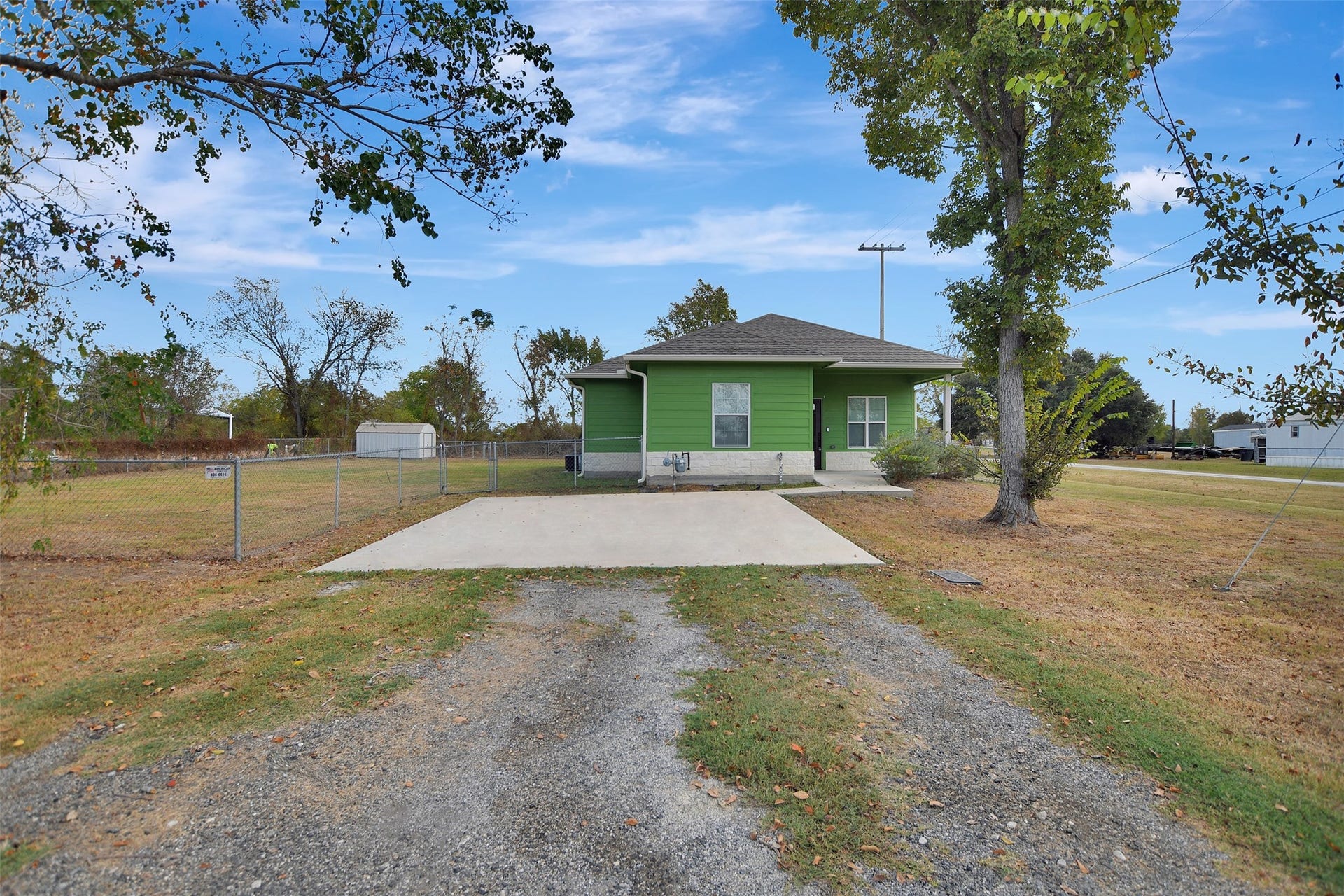 2546 16th Street, Hempstead, TX 77445 Single-story, vibrant green home with a welcoming porch, concrete walkway, and a chain-link fenced yard. The property includes a spacious backyard.