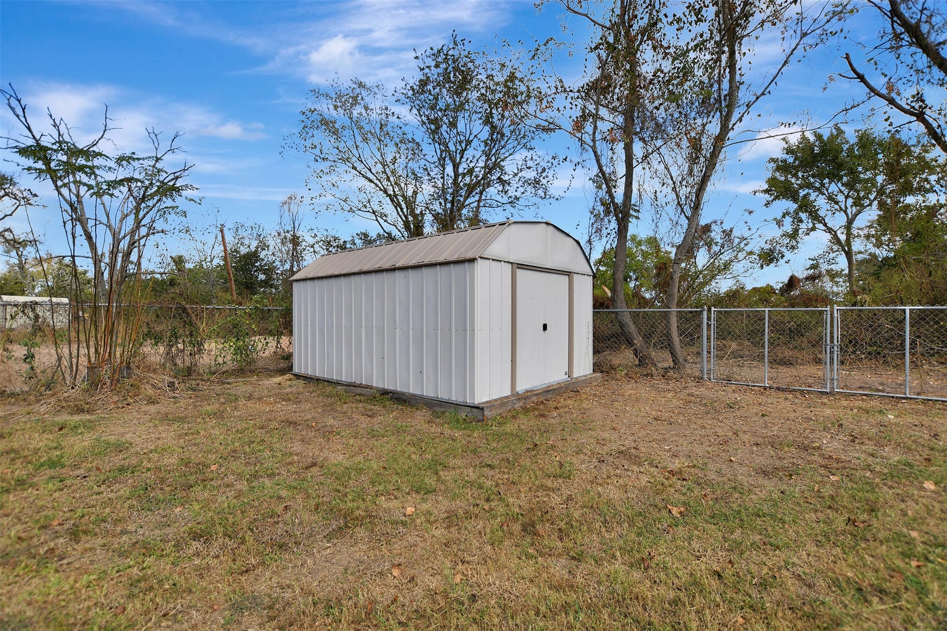 2546 16th Street, Hempstead, TX 77445 This photo shows a backyard with a metal storage shed and chain-link fence.