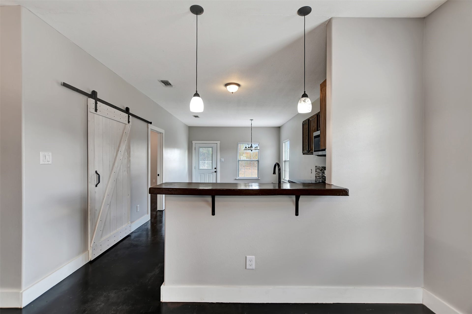 2546 16th Street, Hempstead, TX 77445 This is a modern, open-concept space featuring a sleek kitchen with a breakfast bar, stylish pendant lighting, and a trendy sliding barn door. The laundry room/pantry is behind the barn door.