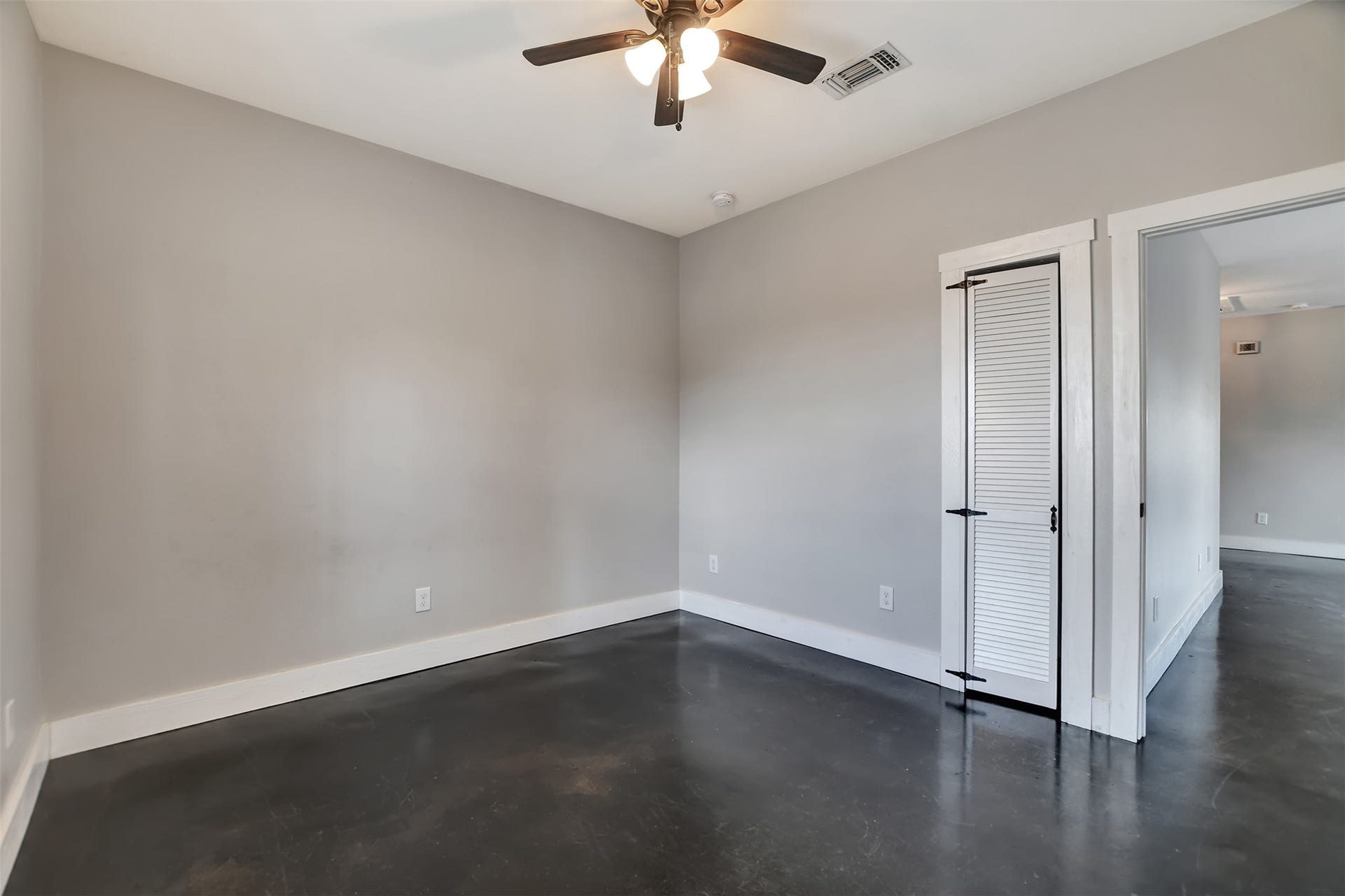 2546 16th Street, Hempstead, TX 77445 This is a spacious bedroom with neutral gray walls, dark stained concrete flooring, and a ceiling fan. It features a small closet. This room is at the front of the home and would be perfect for an office.