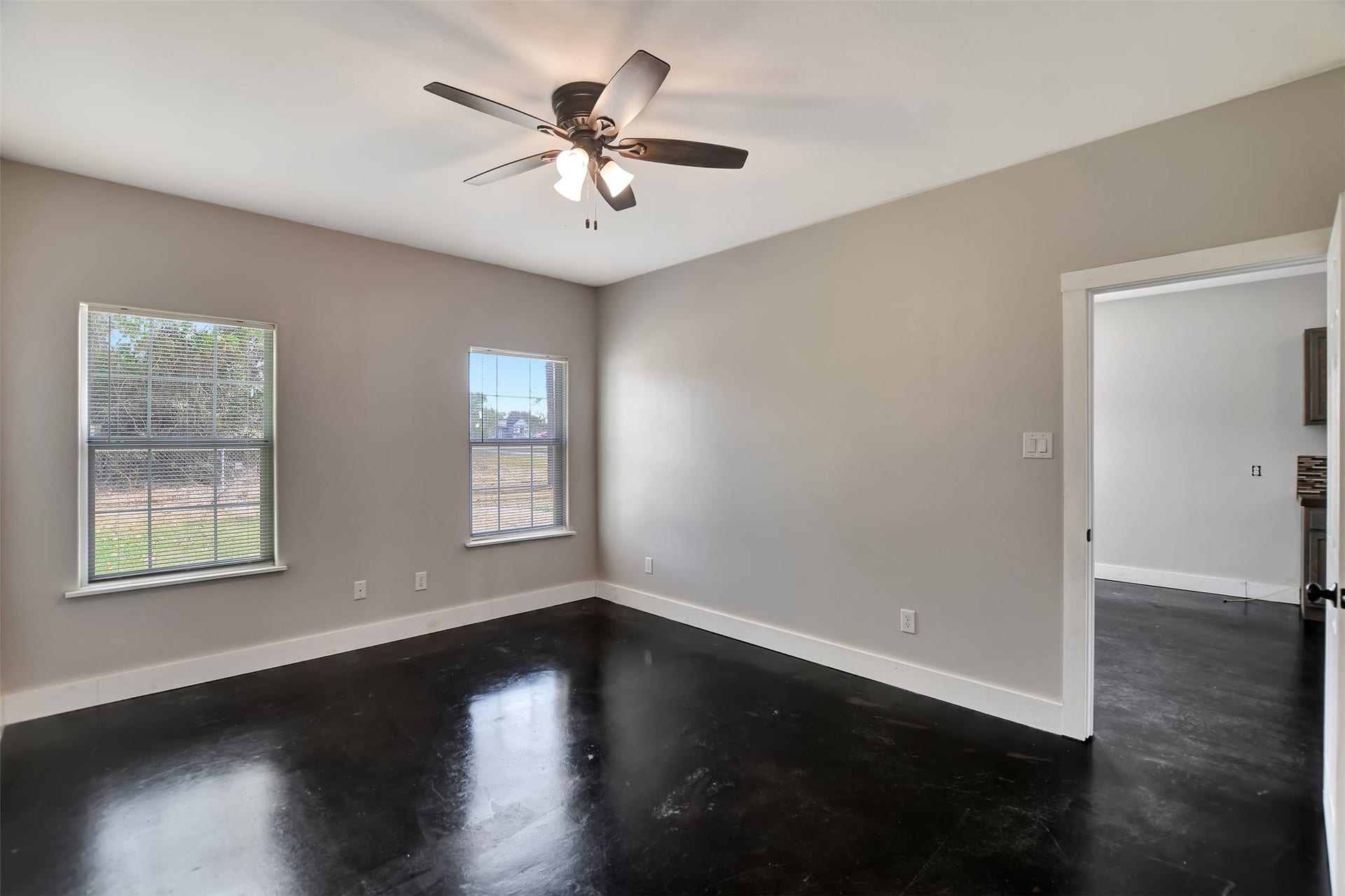 2546 16th Street, Hempstead, TX 77445 This is a spacious primary bedroom, well-lit room with polished dark floors, neutral wall colors, two large windows, and a ceiling fan.