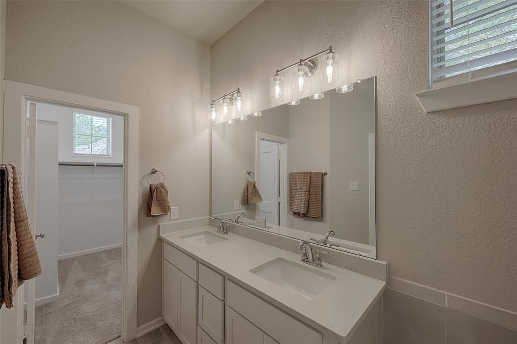 115 Handley Drive, Montgomery, TX 77316 Primary bedroom has double sinks and a large walking in closet with builtin shelving and a window.