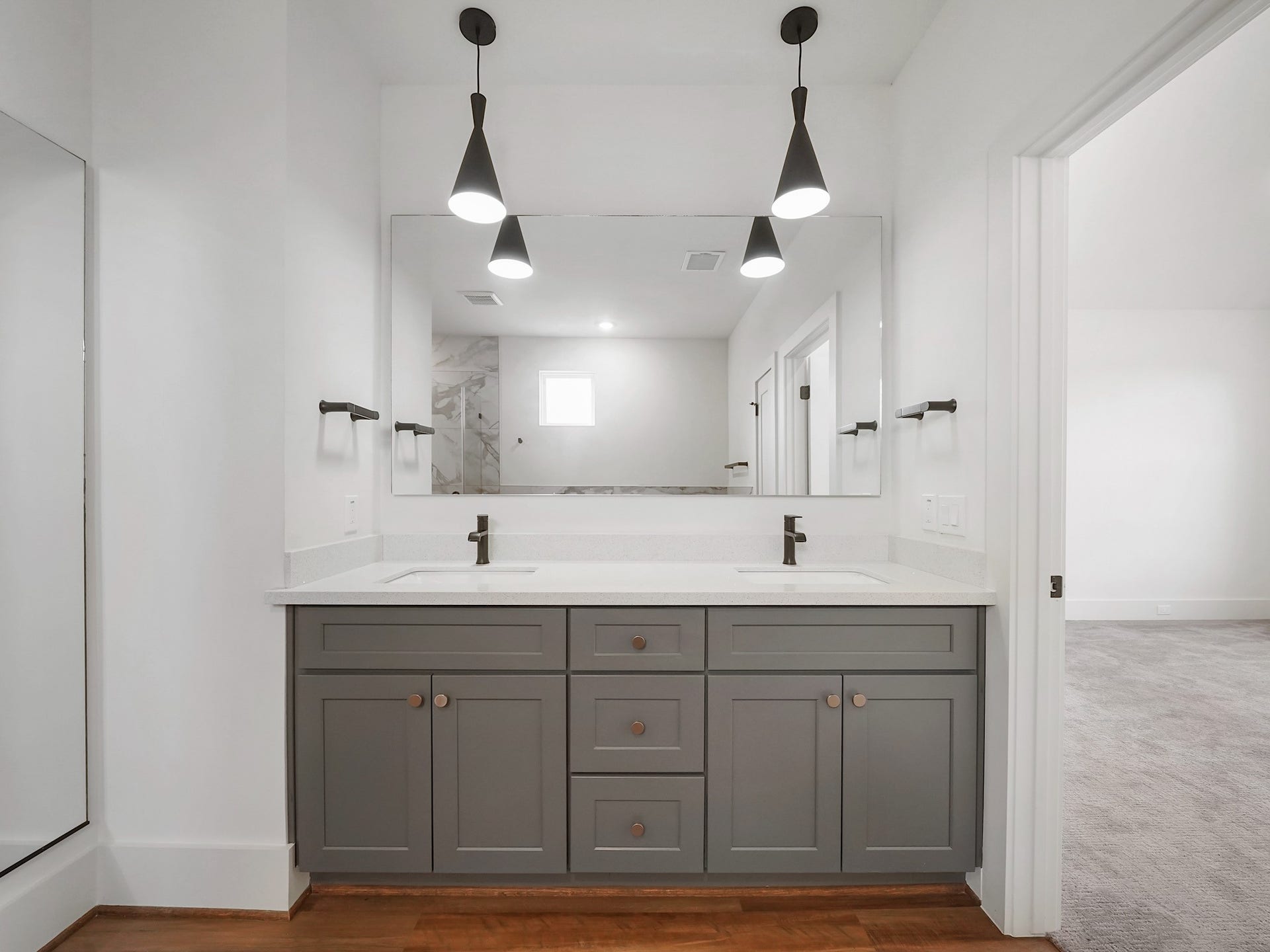881 Rachel Street, #A, Houston, TX 77091 This bathroom features a modern double vanity with gray cabinets, sleek black fixtures, and stylish pendant lighting. The large mirror enhances the space, and the neutral color palette creates a clean, contemporary look.
Photo Disclaimer: Photos are representative of the community and may depict a similar floor plan, model home, or previously completed residence.