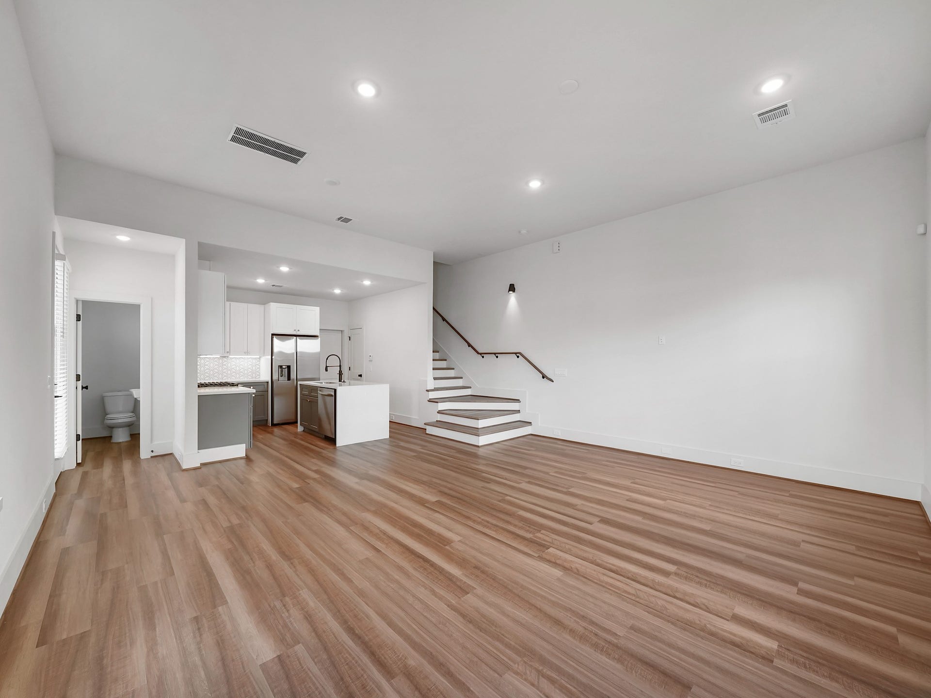 881 Rachel Street, #A, Houston, TX 77091 This spacious and modern open-concept living area features sleek hardwood floors, recessed lighting, and a bright, airy atmosphere. The kitchen boasts stainless steel appliances, an island, and plenty of cabinet space. A staircase leads to the upper level, adding to the room's contemporary design.
Photo Disclaimer: Photos are representative of the community and may depict a similar floor plan, model home, or previously completed residence.