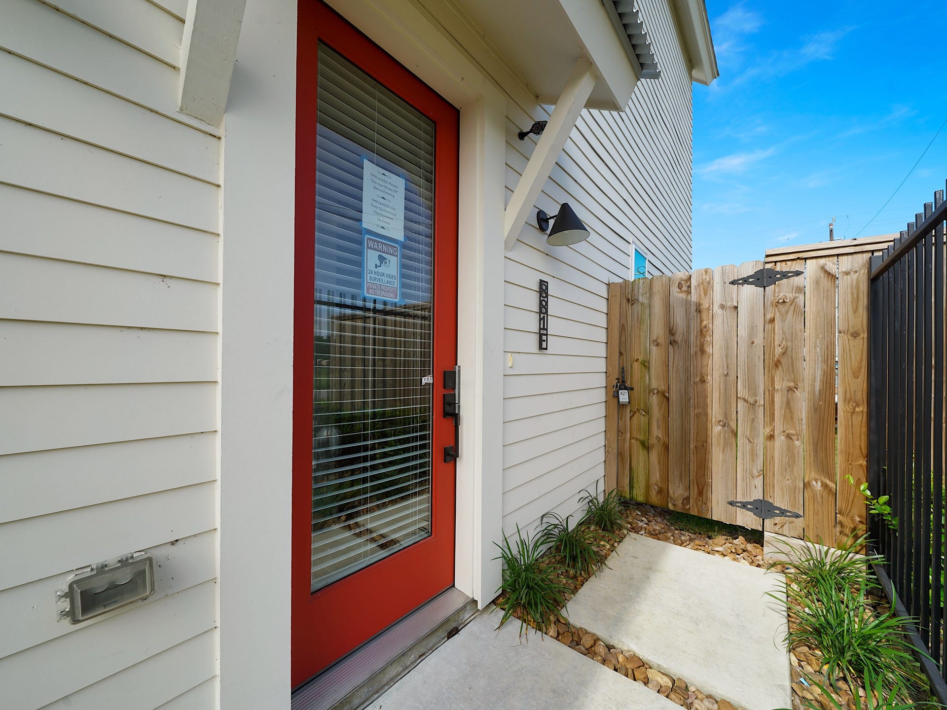 881 Rachel Street, #A, Houston, TX 77091 This photo shows a welcoming entrance with a red door, sidelight windows, and a modern wall light fixture. The area is clean and well-maintained, featuring a wooden privacy gate and small plants along the walkway.
Photo Disclaimer: Photos are representative of the community and may depict a similar floor plan, model home, or previously completed residence.