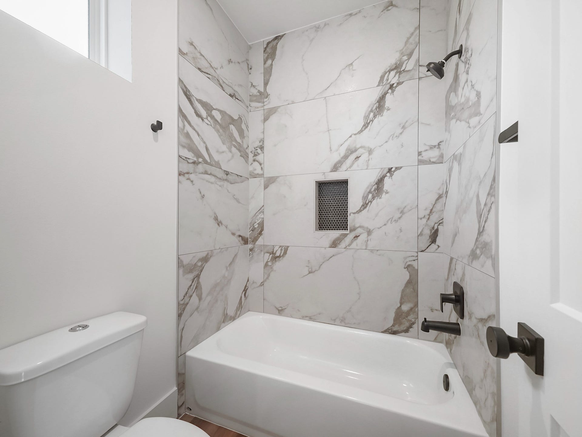 881 Rachel Street, #A, Houston, TX 77091 This bathroom features a sleek design with elegant marble-patterned tiles, a built-in shower niche, and modern fixtures. The space is bright and contemporary, offering a clean and stylish look.
Photo Disclaimer: Photos are representative of the community and may depict a similar floor plan, model home, or previously completed residence.