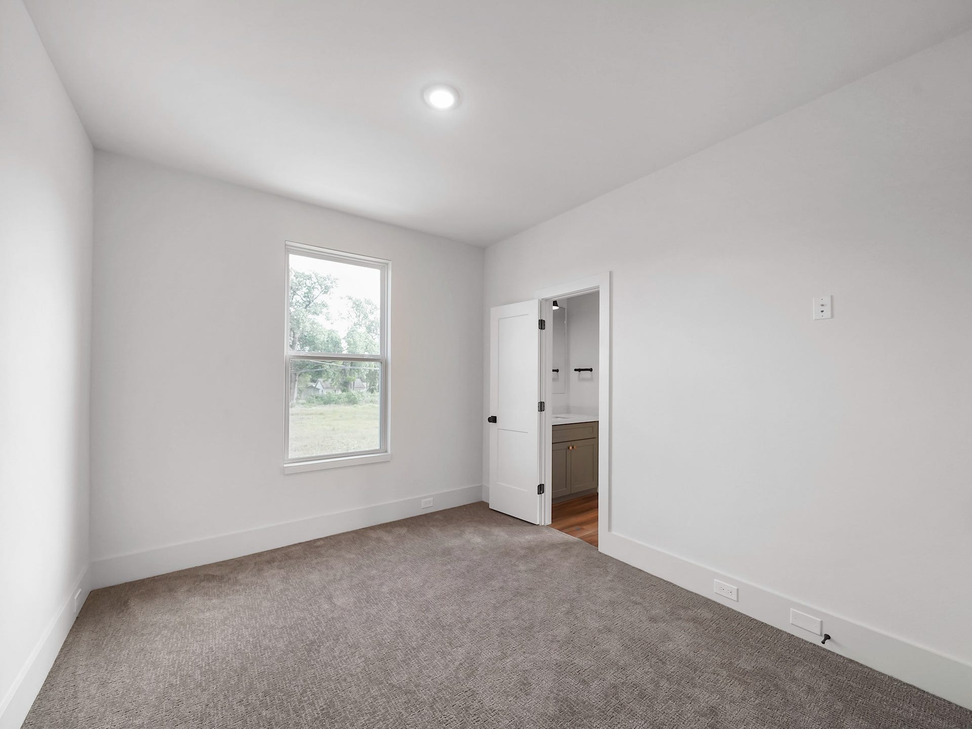 881 Rachel Street, #A, Houston, TX 77091 This is a bright, carpeted bedroom with neutral walls, a window for natural light, and an adjoining bathroom visible through an open door.
Photo Disclaimer: Photos are representative of the community and may depict a similar floor plan, model home, or previously completed residence.