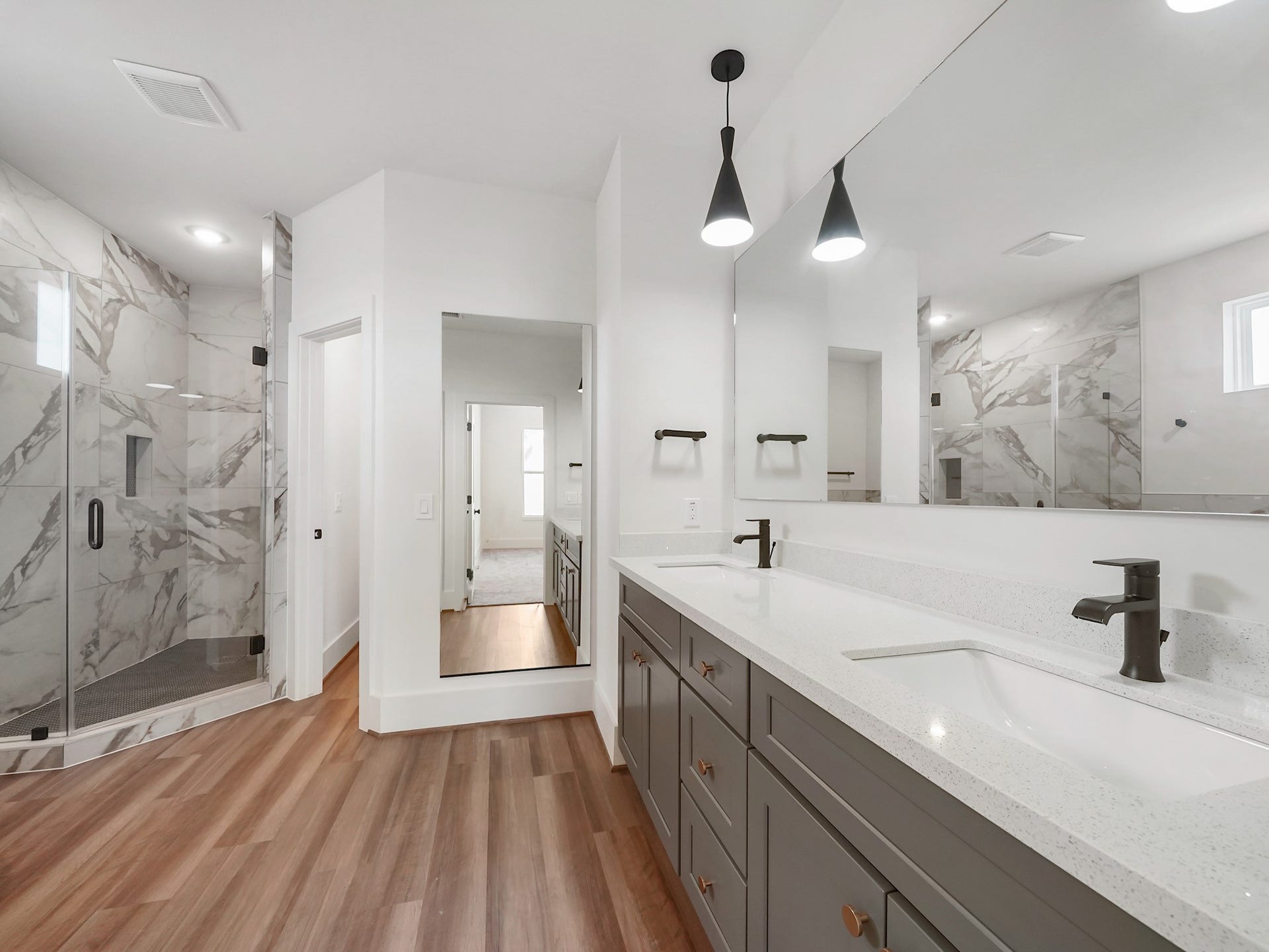 881 Rachel Street, #A, Houston, TX 77091 This bathroom features a spacious double vanity with modern fixtures, a large mirror, and stylish pendant lighting. The room includes a luxurious, marble-tiled walk-in shower and hardwood flooring, creating an elegant and inviting atmosphere.
Photo Disclaimer: Photos are representative of the community and may depict a similar floor plan, model home, or previously completed residence.