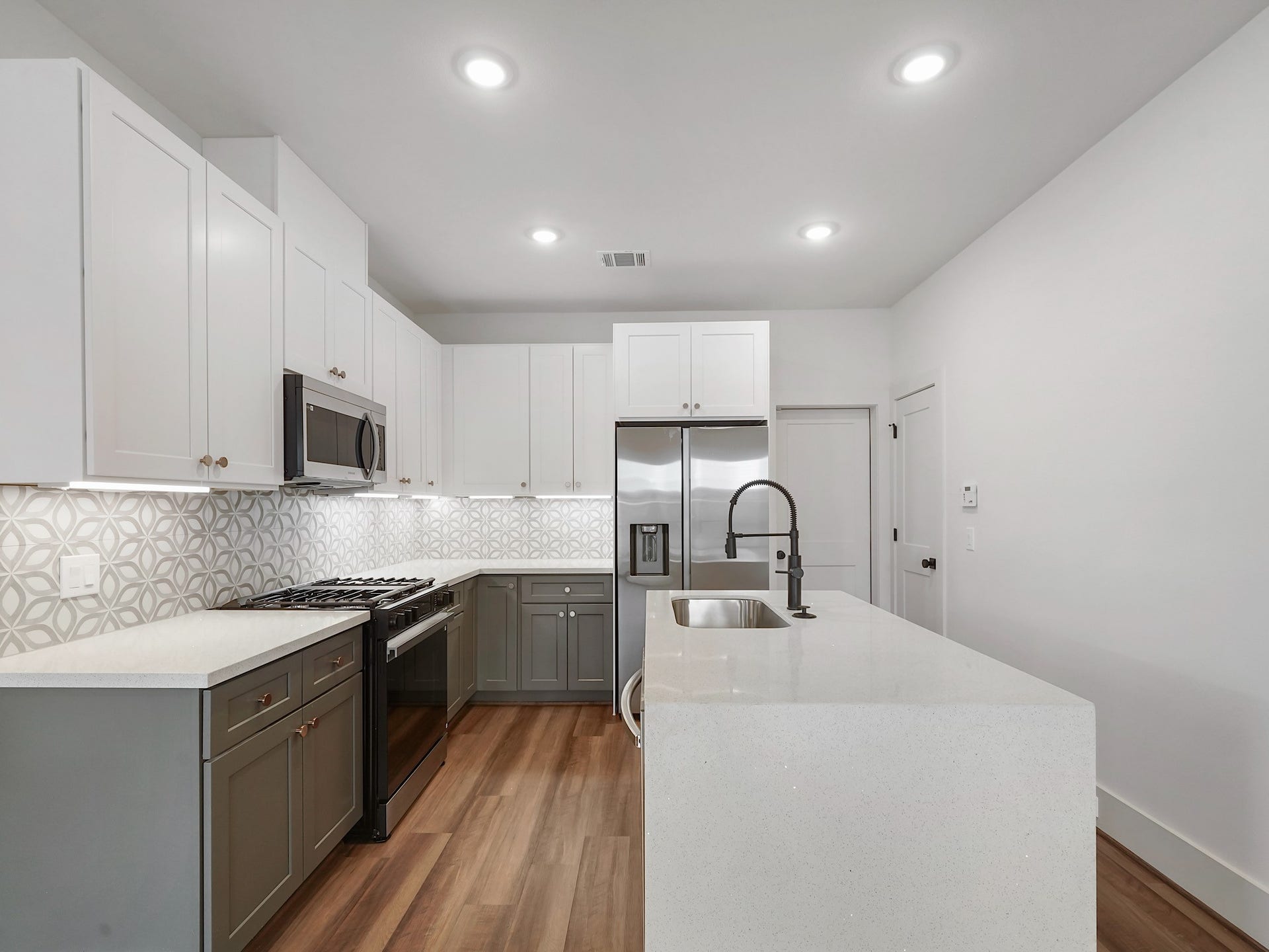 881 Rachel Street, #A, Houston, TX 77091 Modern kitchen with sleek white cabinetry, stainless steel appliances, and a spacious island. Features a stylish geometric backsplash and wood flooring for a contemporary feel.
Photo Disclaimer: Photos are representative of the community and may depict a similar floor plan, model home, or previously completed residence.