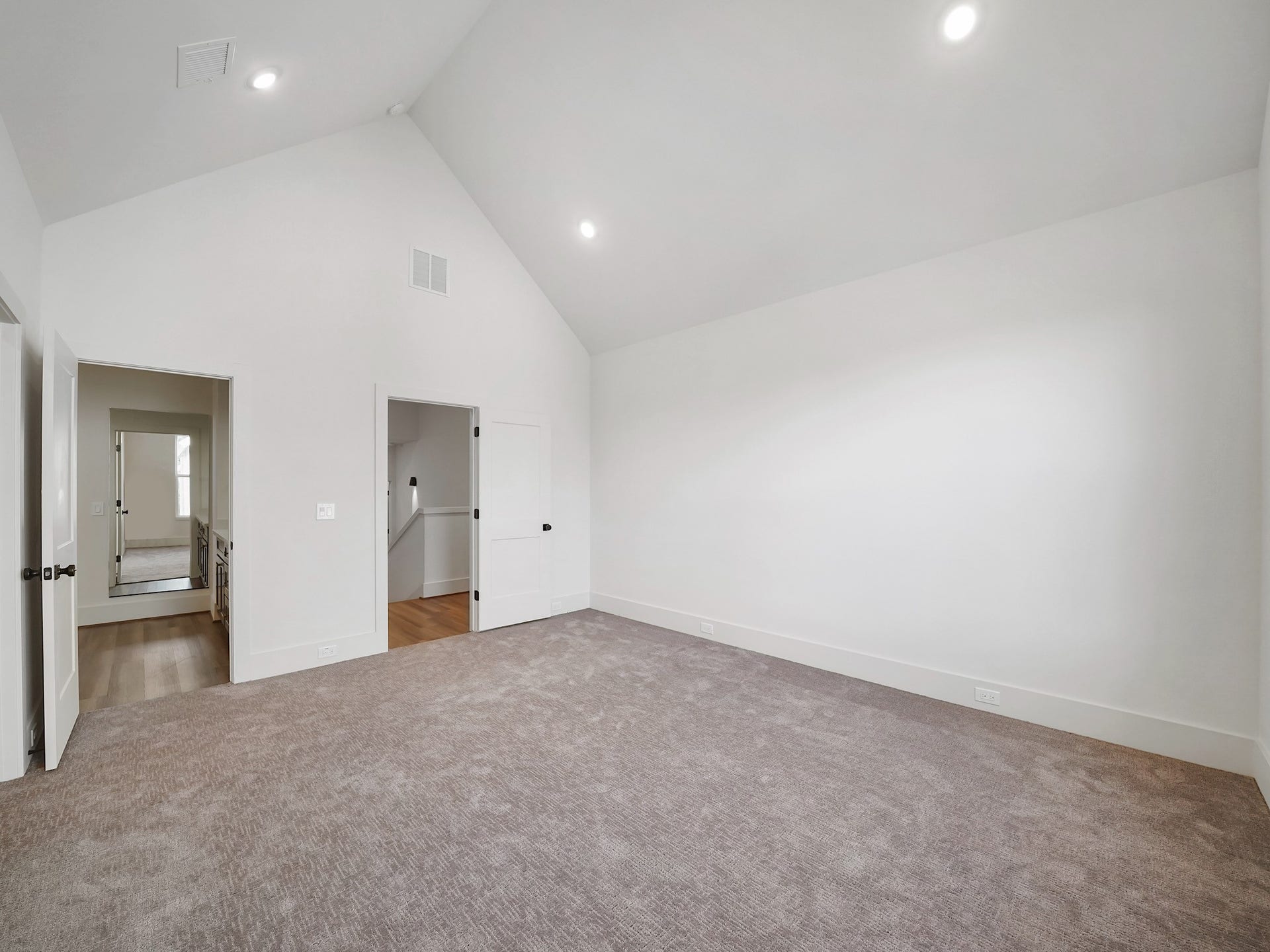 881 Rachel Street, #A, Houston, TX 77091 Spacious room with high ceilings and recessed lighting, featuring neutral carpet and white walls. It has two doors, one leading to a hallway and the other to a room with hardwood flooring. Ideal for a bedroom or living space.
Photo Disclaimer: Photos are representative of the community and may depict a similar floor plan, model home, or previously completed residence.