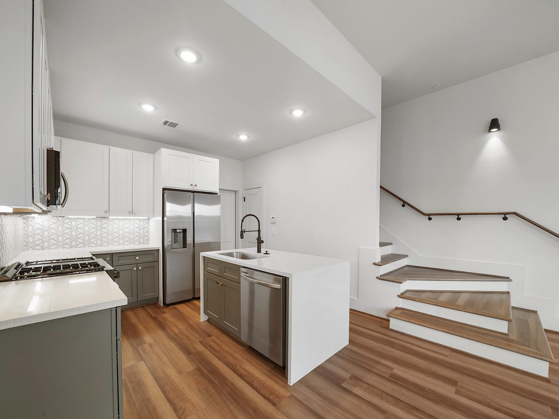 881 Rachel Street, #A, Houston, TX 77091 This modern kitchen features sleek white cabinets, stainless steel appliances, and a stylish tile backsplash. The open layout includes an island with a sink and dishwasher, complemented by warm wood flooring and a nearby staircase with contemporary design.
Photo Disclaimer: Photos are representative of the community and may depict a similar floor plan, model home, or previously completed residence.