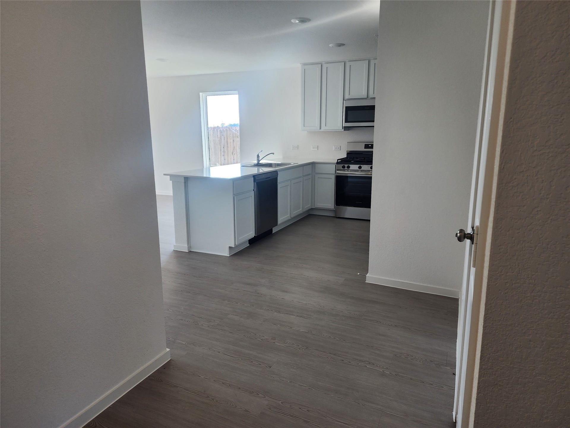 17307 Adina Creek Court, Crosby, TX 77532 This photo showcases a modern, open kitchen with sleek white cabinetry, stainless steel appliances (included) from view of entryway hallway.