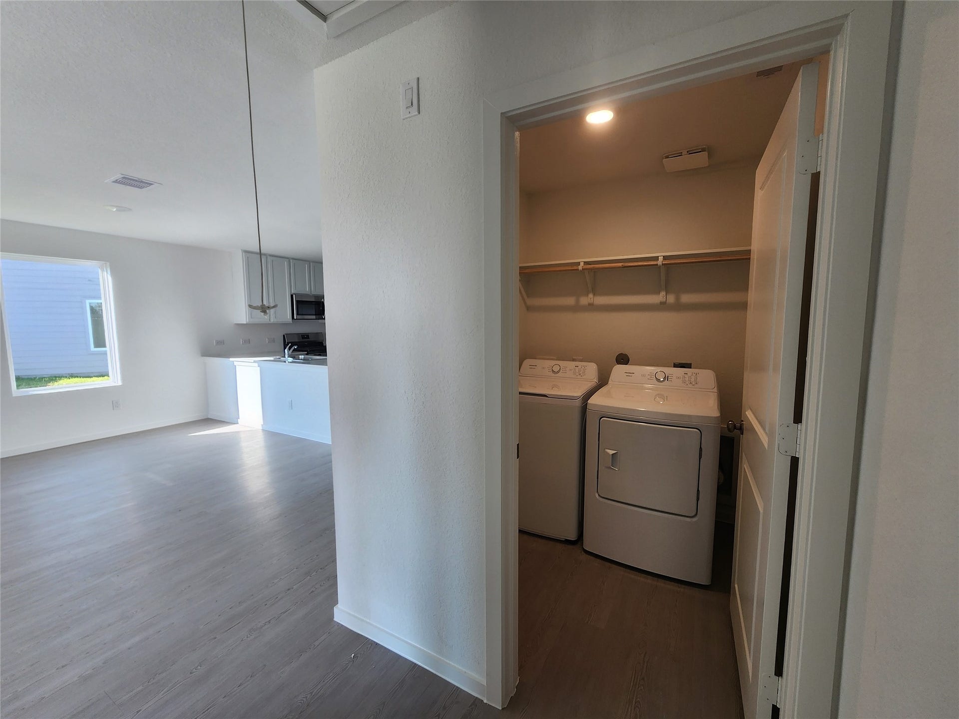 17307 Adina Creek Court, Crosby, TX 77532 Bright, open living space with light wood flooring and a separate laundry room equipped with a washer and dryer located across from the primary bedroom.