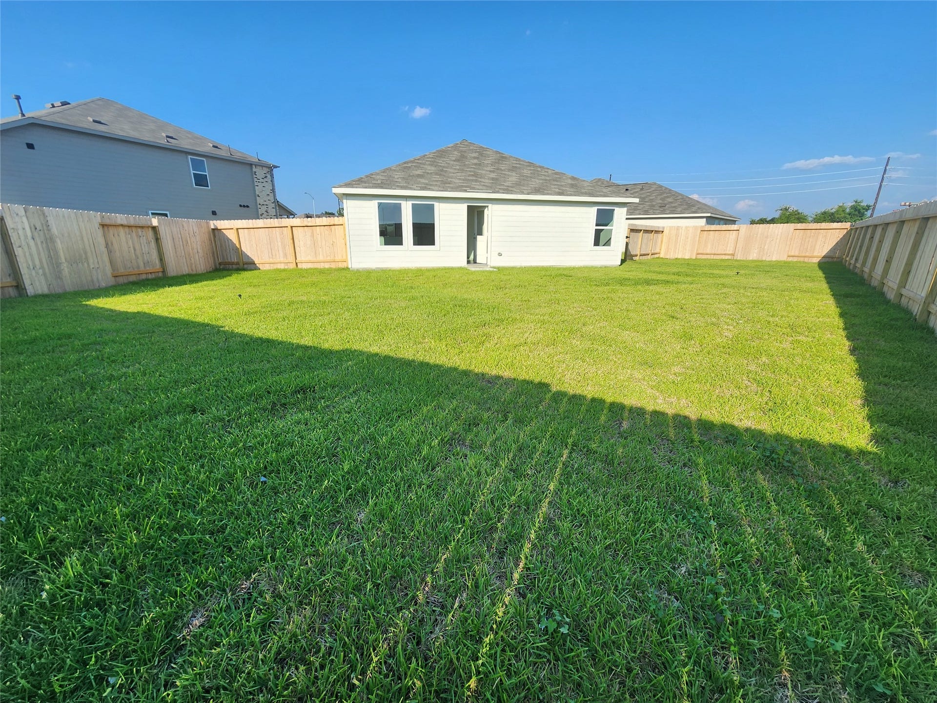 17307 Adina Creek Court, Crosby, TX 77532 Spacious backyard with well-maintained lawn, bordered by a wooden privacy fence, perfect for outdoor activities.