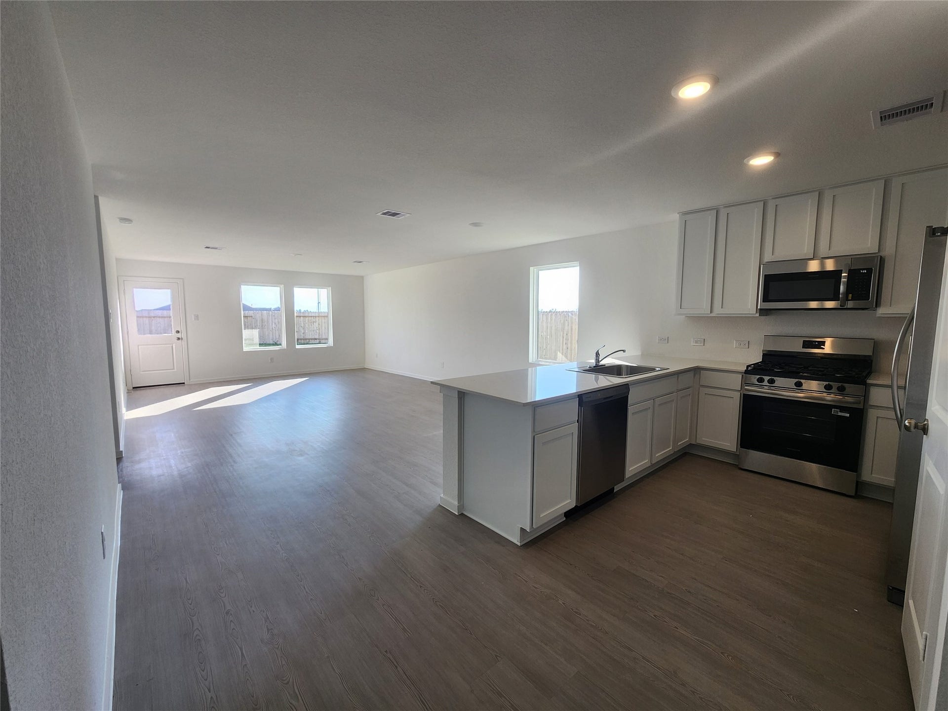 17307 Adina Creek Court, Crosby, TX 77532 View of open-concept living/dinning space featuring a bright kitchen with stainless steel appliances and ample counter space. The adjoining living area is spacious with large windows and a door leading outside, providing plenty of natural light.