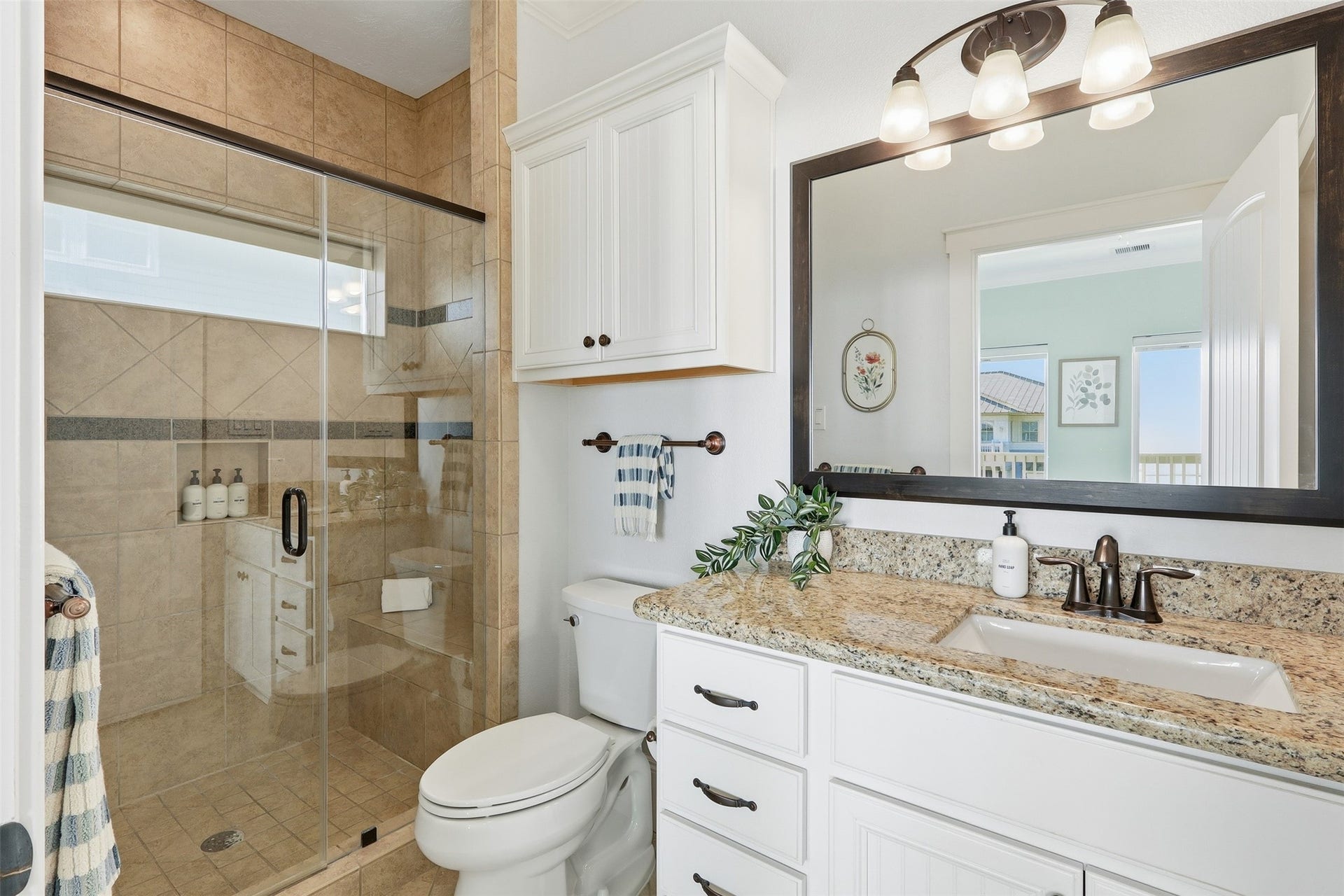 11622 Beachside, Galveston, TX 77554 This bathroom features a spacious glass-enclosed shower, a granite countertop with a built-in sink, and elegant dark fixtures.