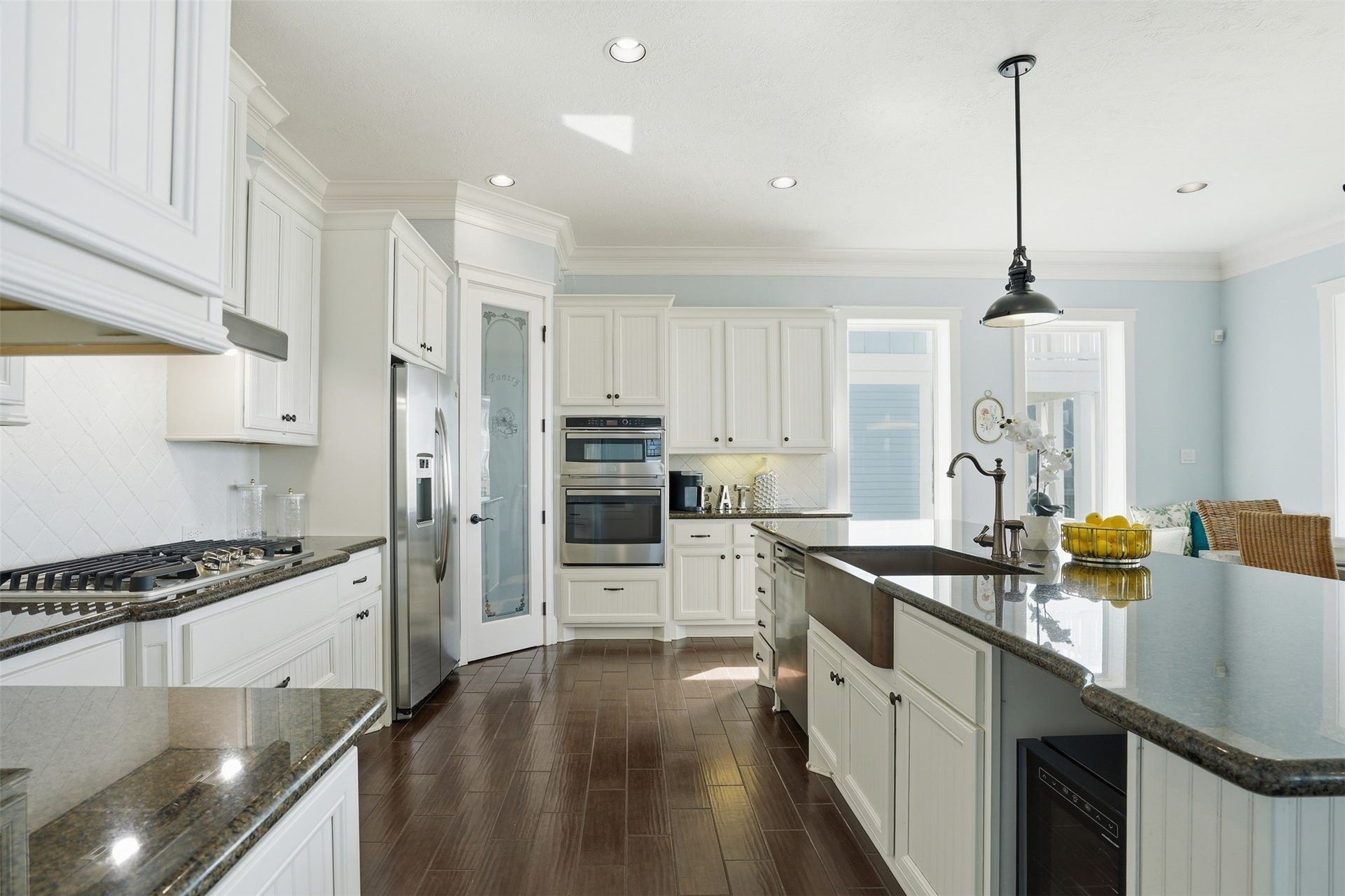 11622 Beachside, Galveston, TX 77554 This spacious and bright kitchen features modern white cabinetry, stainless steel appliances, and a central island with seating with an adjacent dining area.