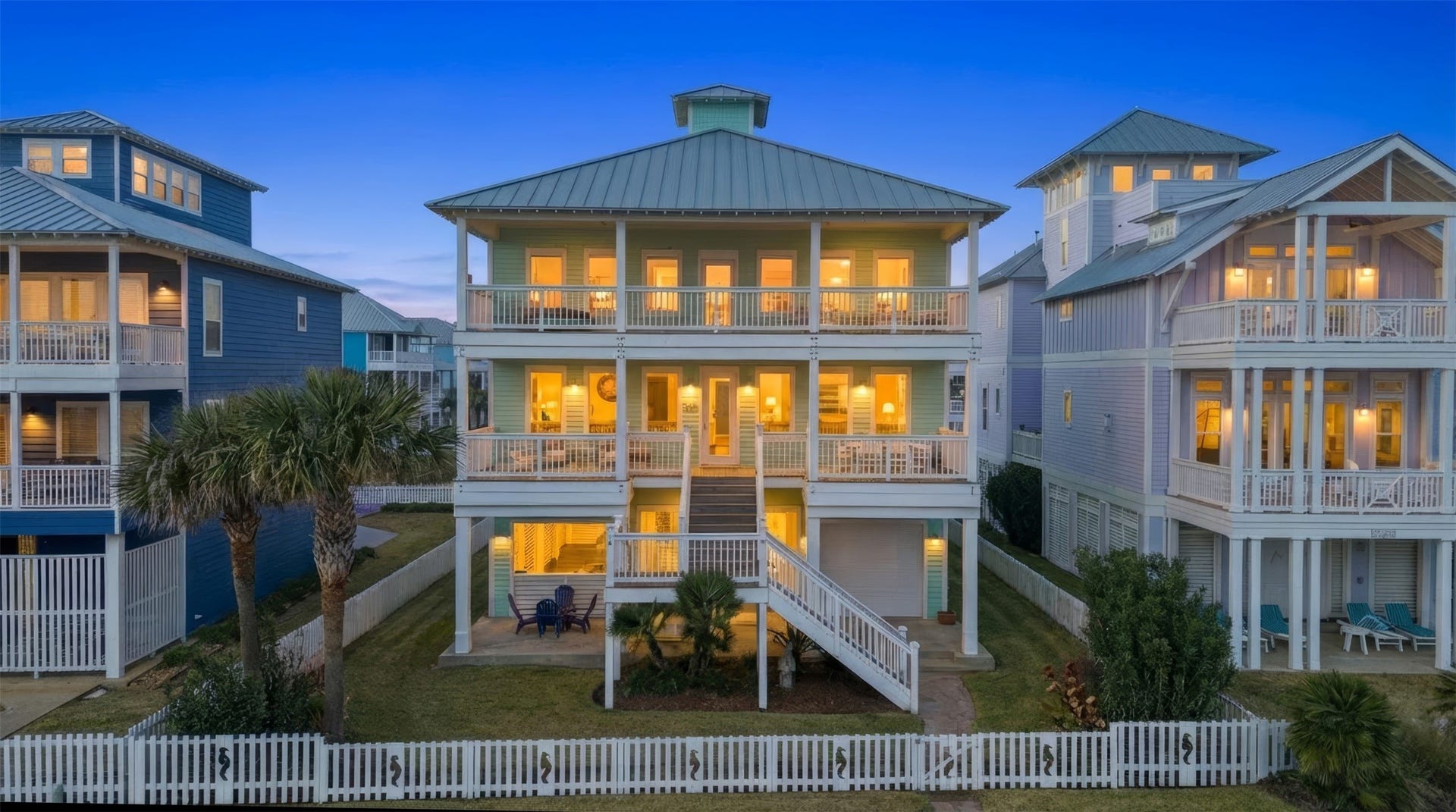 11622 Beachside, Galveston, TX 77554 A charming coastal home with a spacious front porch and balcony, surrounded by a white picket fence.
