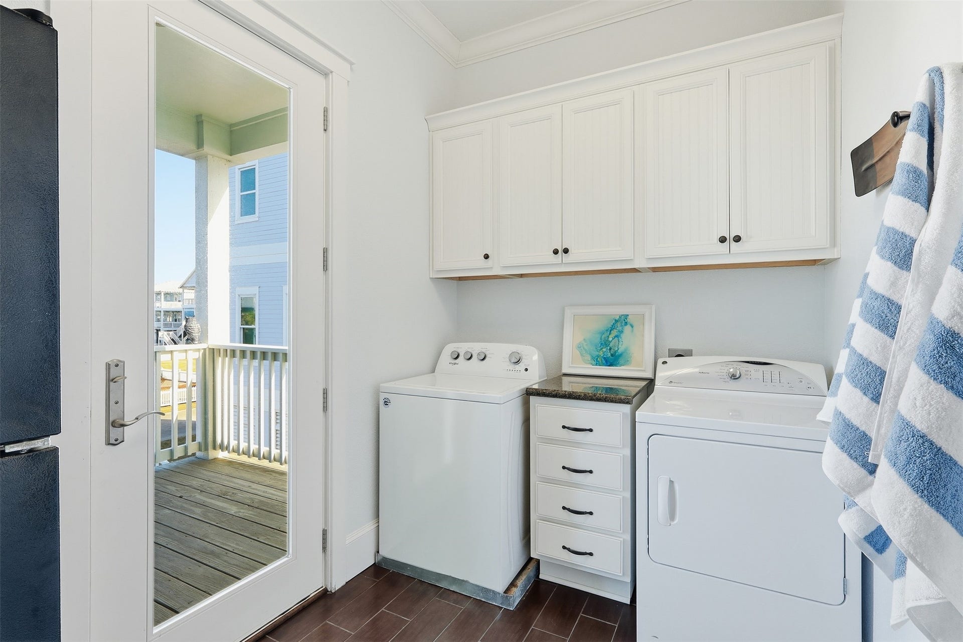 11622 Beachside, Galveston, TX 77554 This is a bright and functional laundry room featuring white cabinetry and a side-by-side washer and dryer.