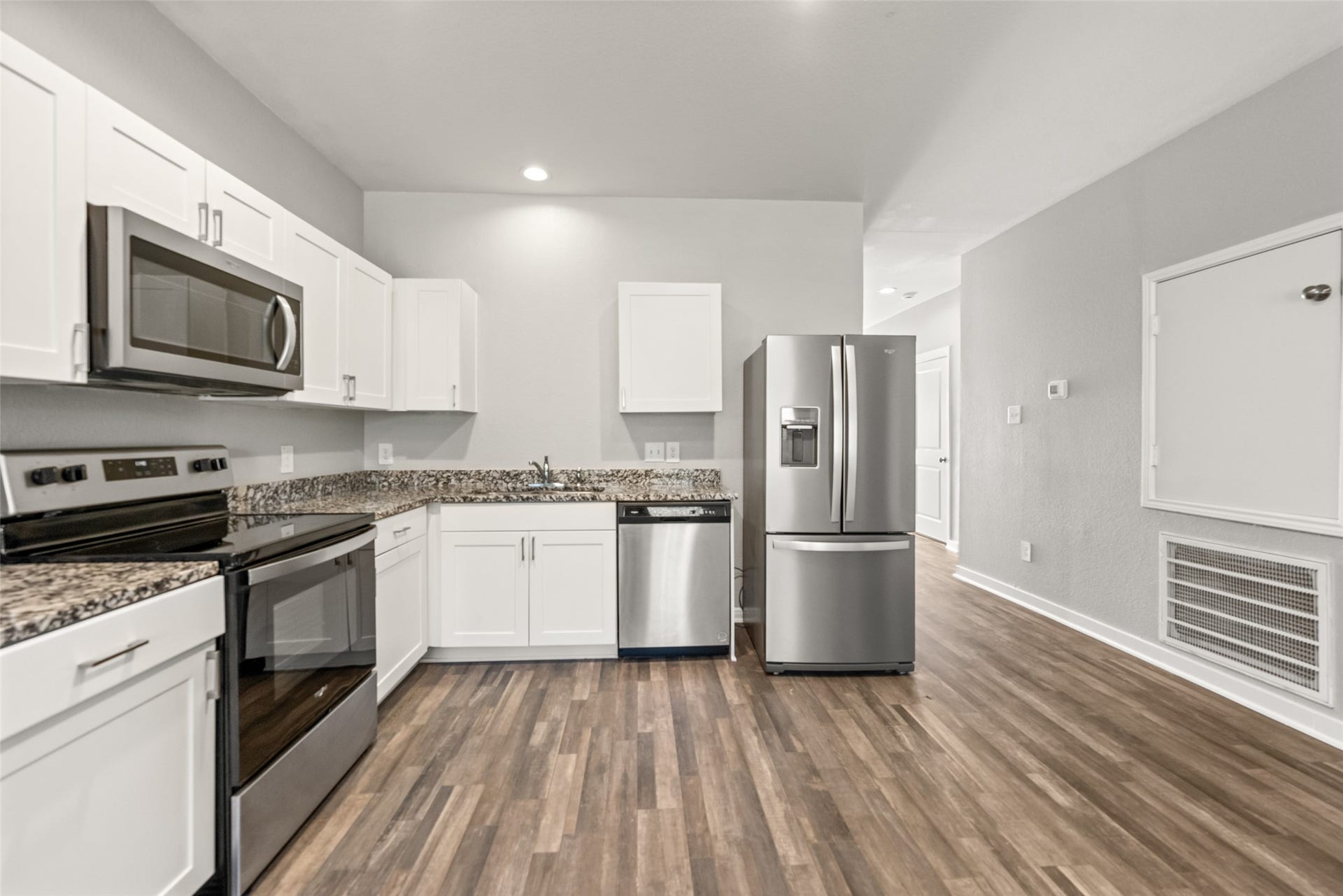2537 18th Street, Hempstead, TX 77445 Modern kitchen featuring white cabinetry, granite countertops, stainless steel appliances, and wood-look flooring.