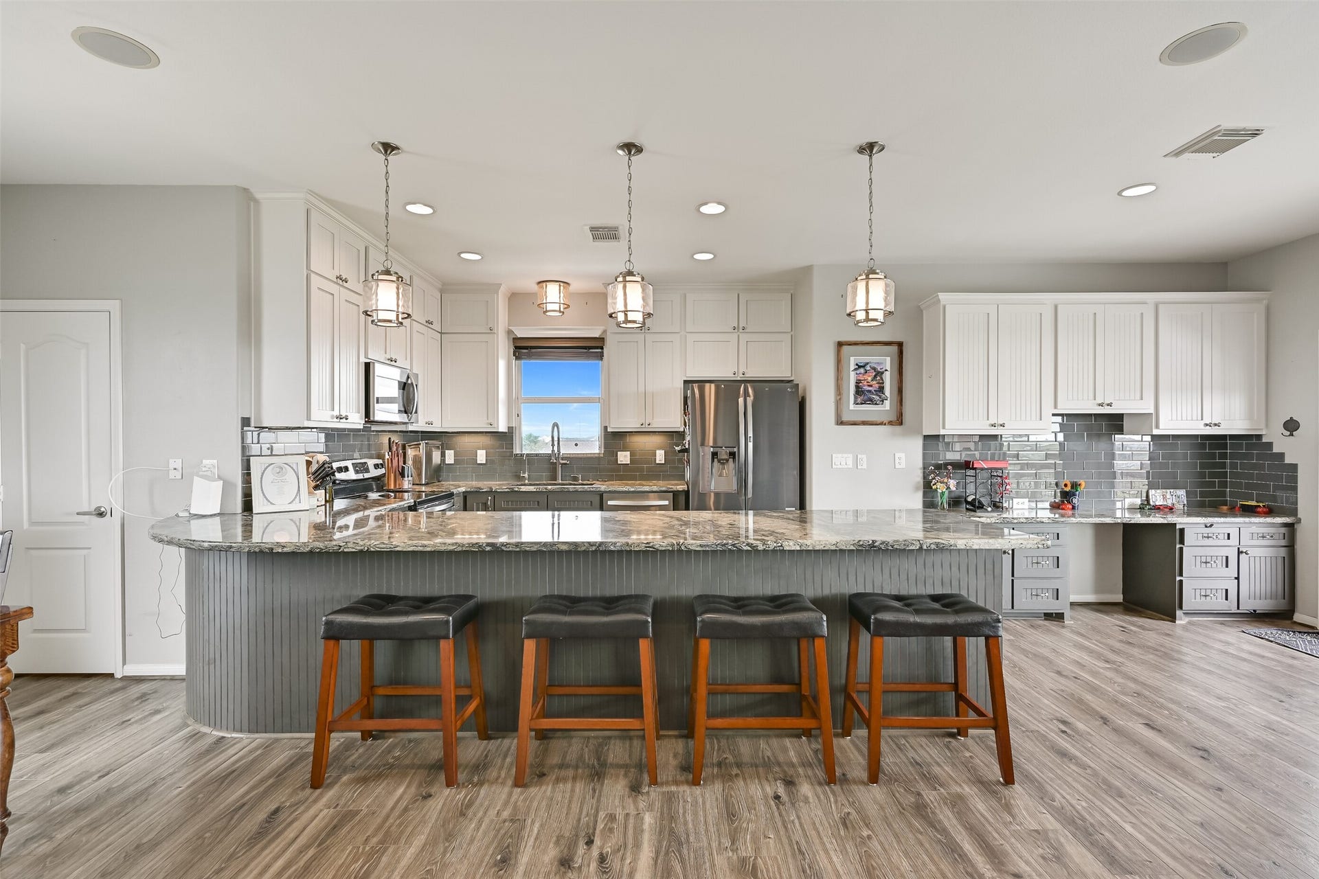 7119 Beau Rue Street, Hitchcock, TX 77563 Notice the oversized peninsula island lathed in stunning silver cloud granite with a contrasting beadboard wall kick. The door to the Left reveals an oversized walk-in pantry.
