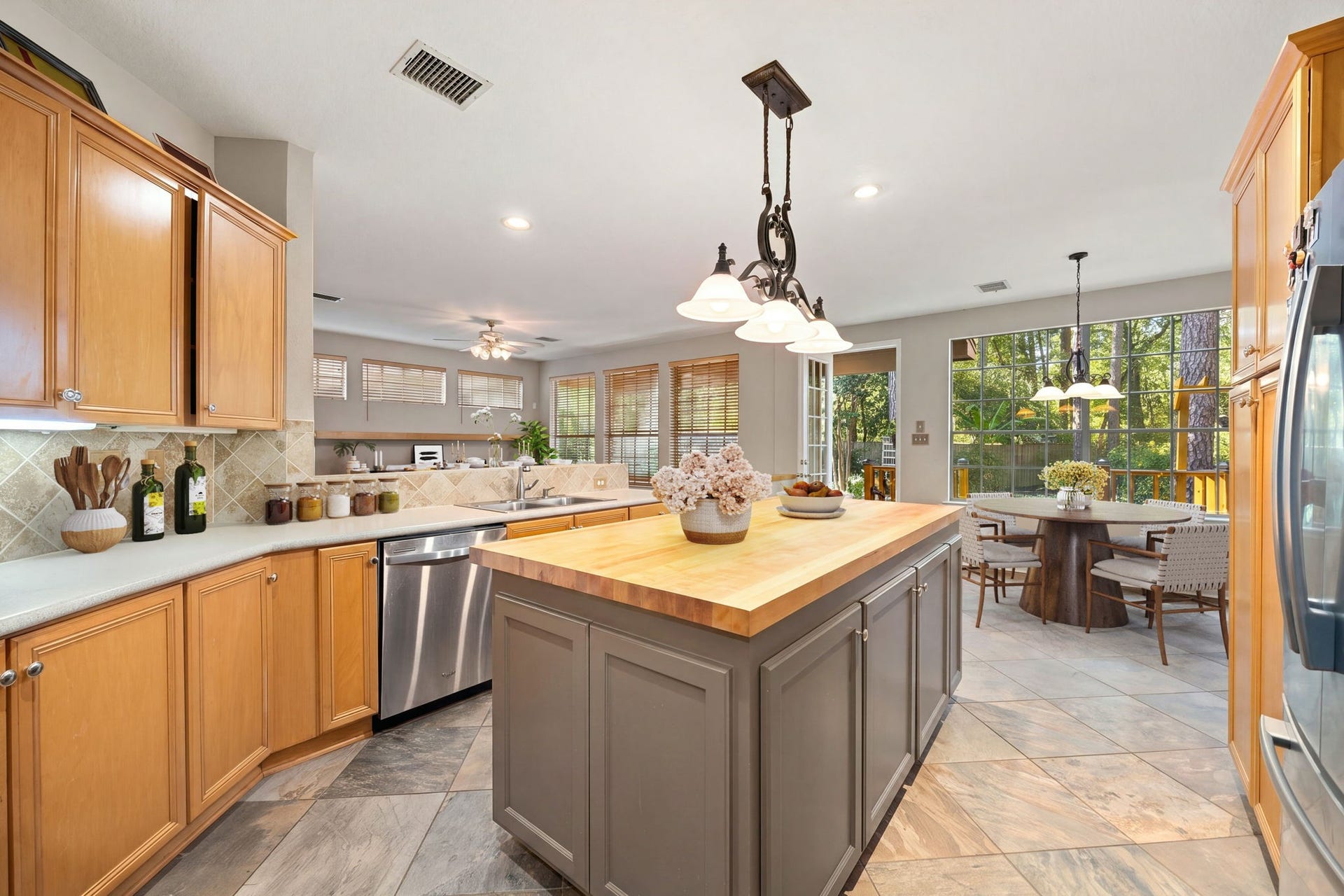 205 Purple Slate Place, The Woodlands, TX 77381 Designed for effortless cooking and casual dining, this spacious kitchen flows seamlessly into a bright breakfast nook surrounded by nature. The layout boasts an impressive central island perfect for food prep. Natural light streams through an expansive bank of backyard windows and a glass patio door, creating an incredibly warm, bright, and welcoming atmosphere across the tile floor. *Virtually Staged
