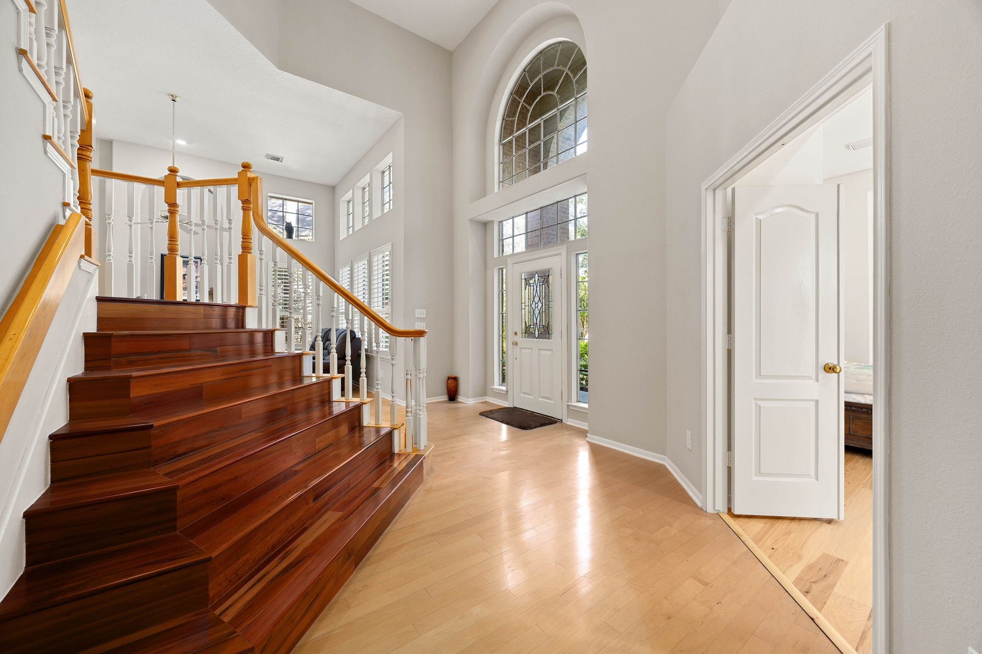 205 Purple Slate Place, The Woodlands, TX 77381 The impressive grand staircase features rich, polished Brazilian Kobe wood steps that beautifully contrast with the bright, open-concept entryway. Towering ceilings and expansive multi-tier windows create an exceptionally airy atmosphere, filling the space with sunlight as soon as you step through the decorative glass front door. This elegant layout effortlessly directs guests into the main living zones while offering an upscale, sophisticated welcome.