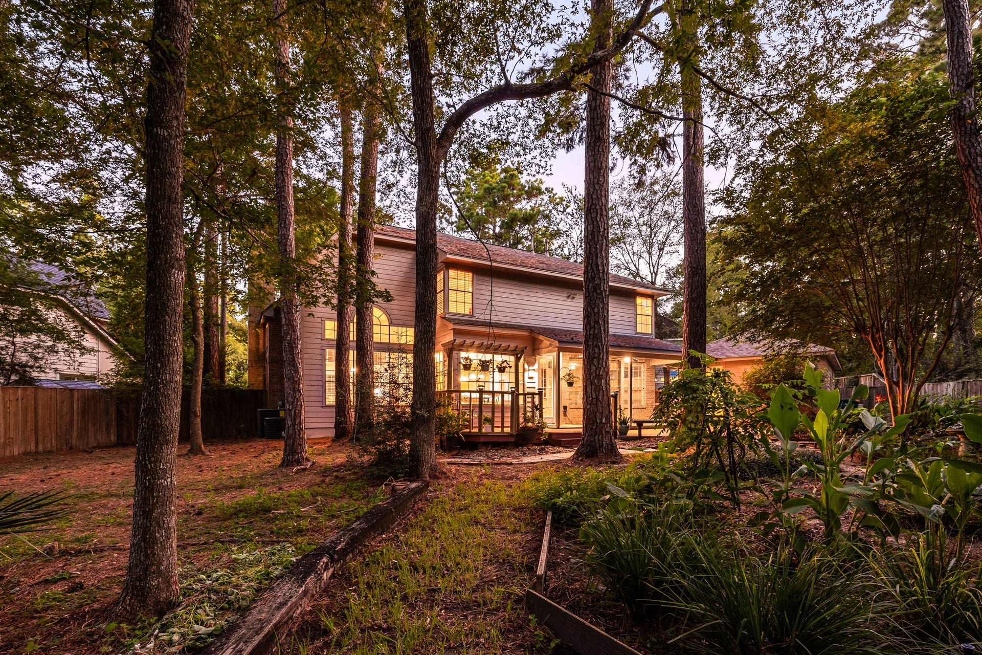 205 Purple Slate Place, The Woodlands, TX 77381 This captivating wide-angle perspective highlights the true scale of the private, heavily wooded lot, showcasing the home completely nestled within nature.