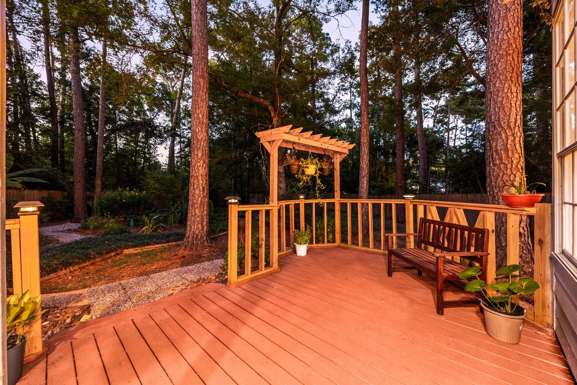 205 Purple Slate Place, The Woodlands, TX 77381 Enjoy the perfect spot for morning coffee or evening relaxation on this custom-built raised deck. The structural design showcases a classic wooden pergola frame integrated seamlessly into the corner railing, adding a distinct transitional charm to the backyard layout.