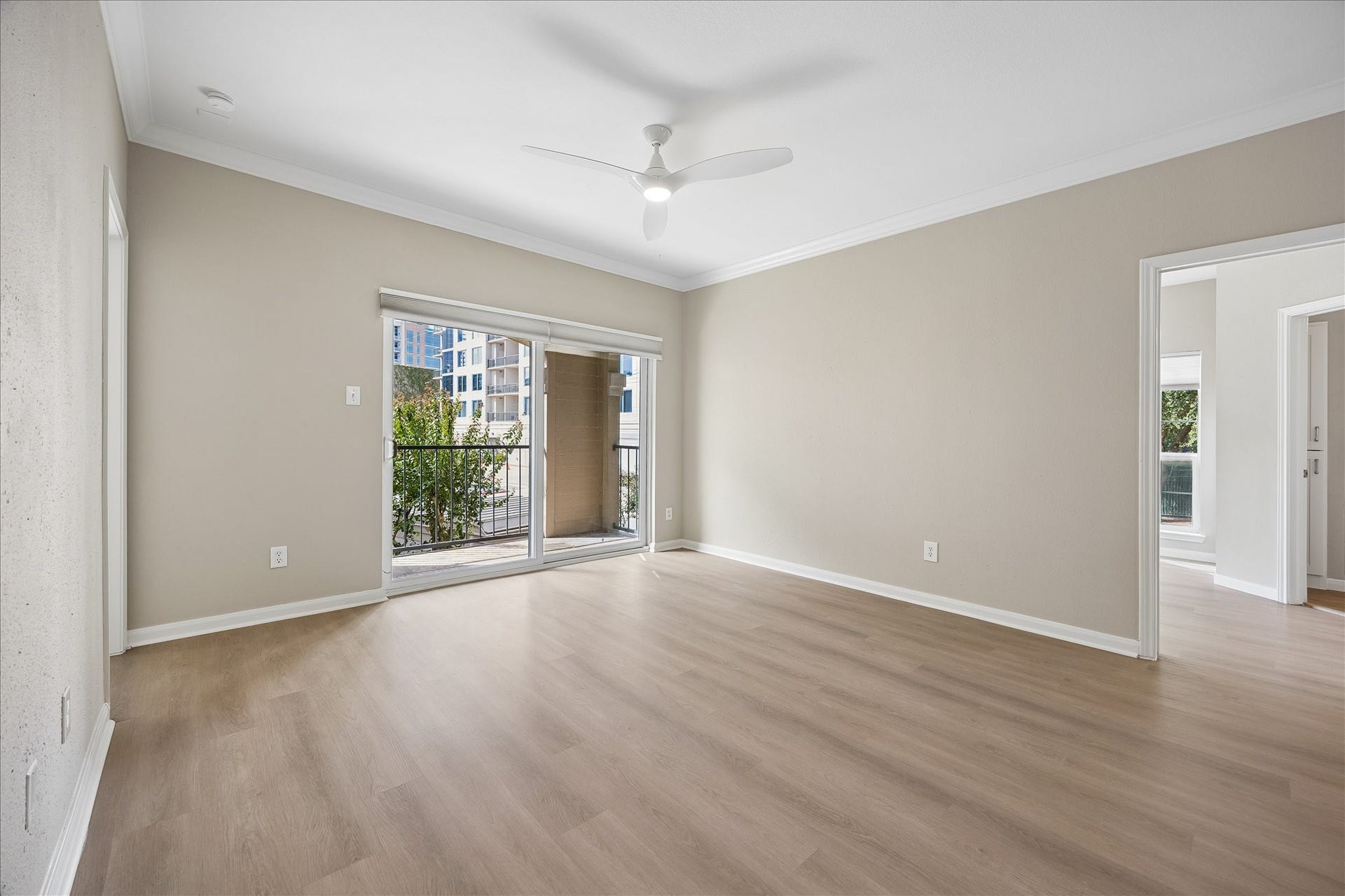 3231 Allen Parkway, #1216, Houston, TX 77019 One more view of the large living room w/new LVT flooring throughout, crown molding & new ceiling fan w/ light. Large sliding glass doors fill the space w/ natural light & lead to the private covered balcony overlooking beautifully landscaped community grounds. Door to the right leads to the primary suite.