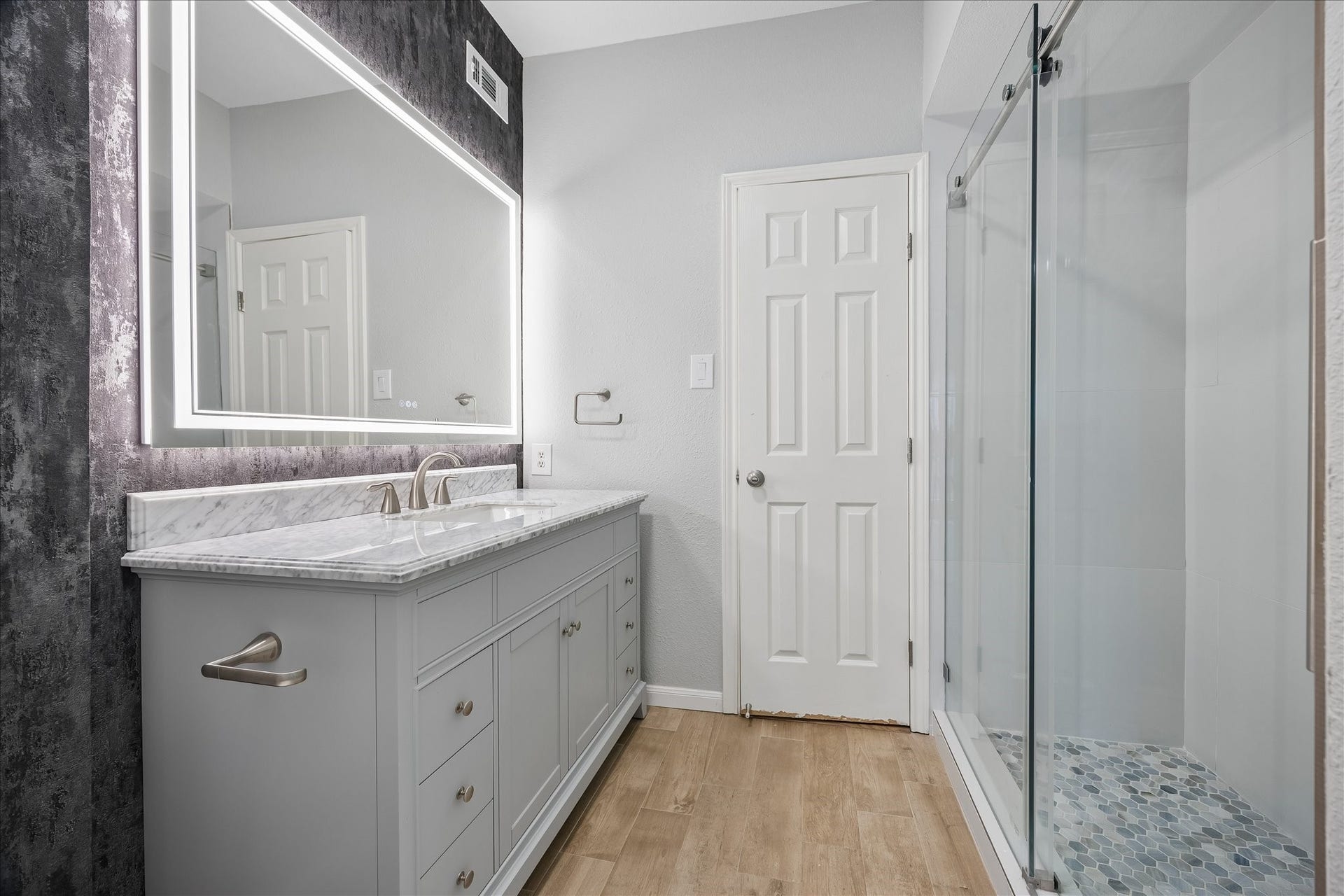 3231 Allen Parkway, #1216, Houston, TX 77019 Beautifully extensively updated secondary bathroom featuring a vanity w/ a LED lighted vanity mirror. Notice the walk-in shower w/ frameless sliding glass door, handheld showerhead & hexagon tile flooring. Decorative accent wallpapered wall adds a stylish finishing touch!
