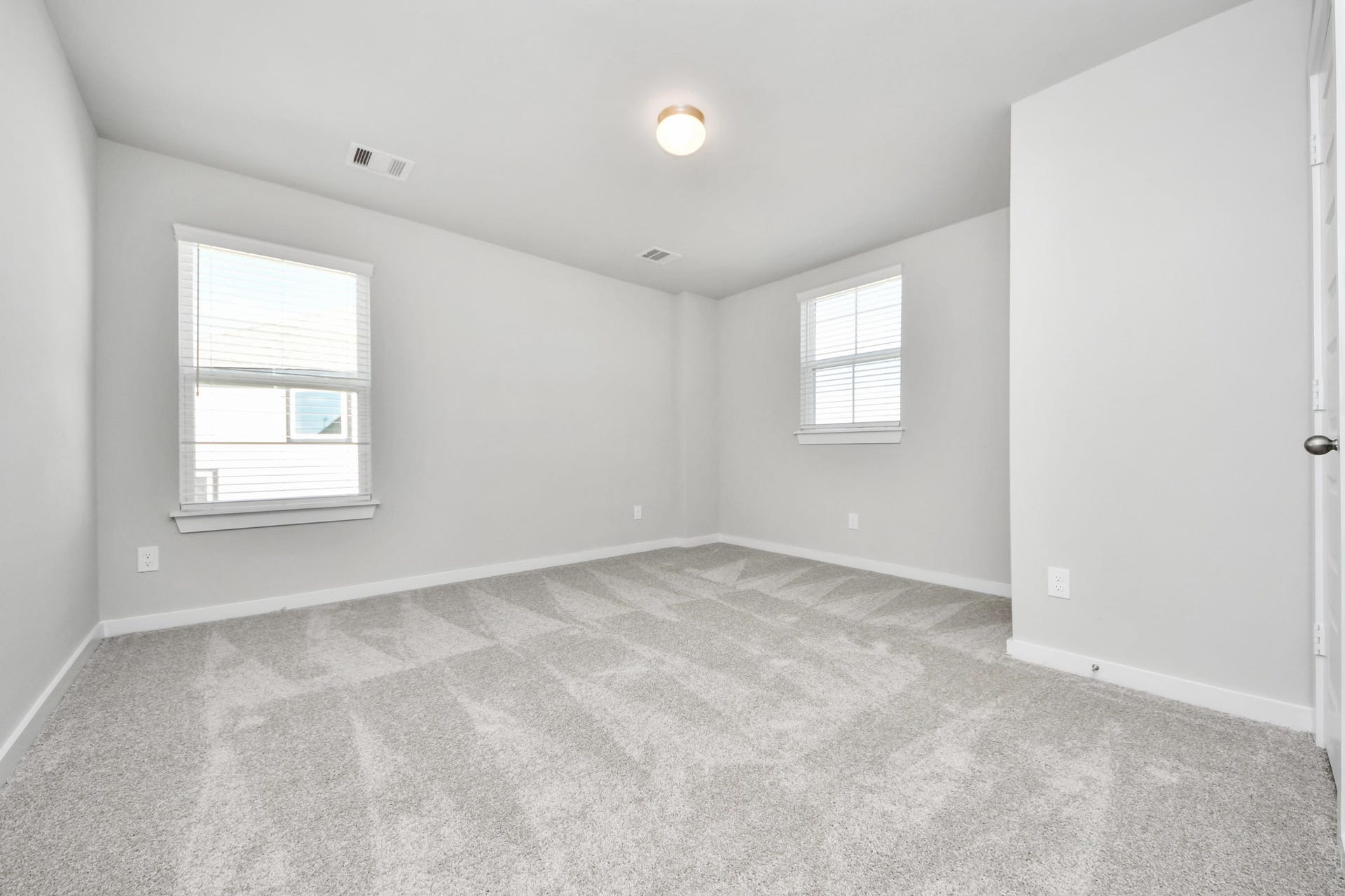 Secondary bedroom features plush carpeting, large windows that let in plenty of natural light, bright paint, and spacious closets. Sample photo of completed home with similar floor plan. Actual colors and selections may vary.
