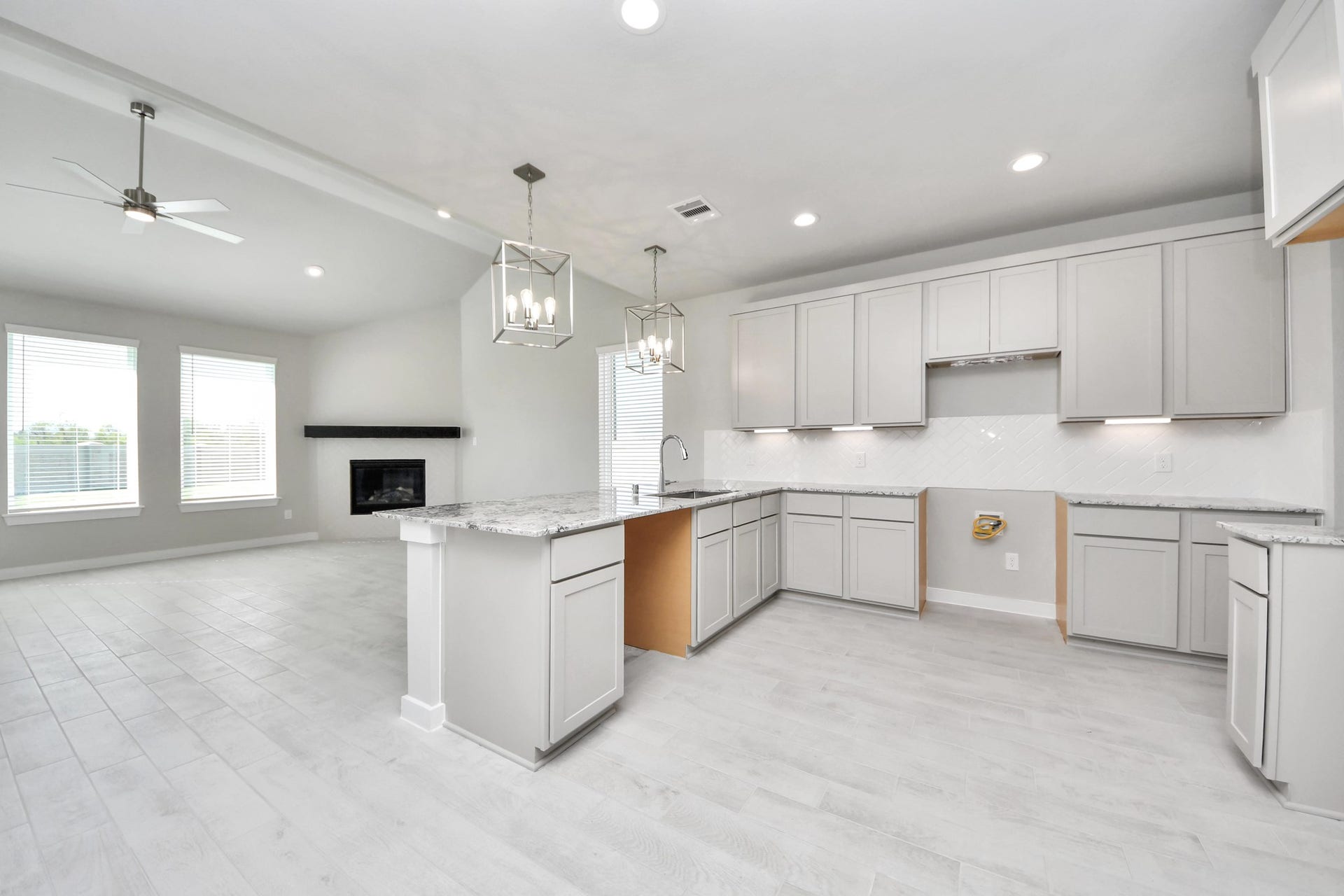 This kitchen is truly a chef's dream! This haven Boasts high ceilings, recessed & pendant lighting, stained wood cabinets, granite countertops, stainless steel appliances, a modern tile backsplash.  All of this overlooks your expansive family room, creating a perfect space for culinary delights and family gatherings. Sample photo of completed home with similar floor plan. Actual colors and selections may vary.
