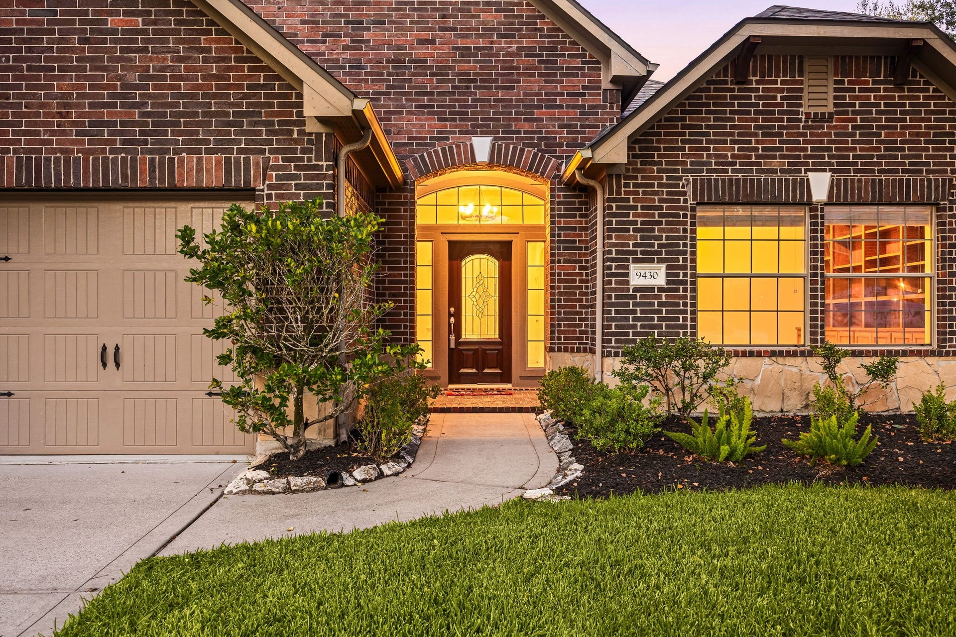 9430 Amethyst Arbor Lane, Katy, TX 77494 A welcoming, curved walkway sets the stage for exceptional curb appeal, leading you directly to a grand arched entryway where a classic glass-paneled front door beckons you inside. The beautifully detailed brick facade and pristine front landscaping immediately establish an inviting first impression before you even step across the threshold.