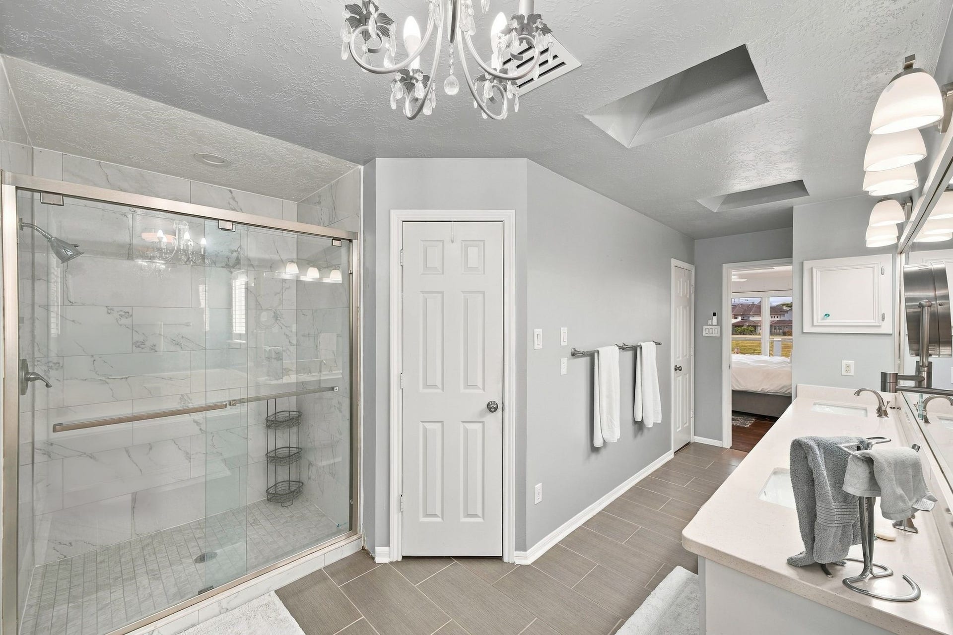 932 Plantation Street, League City, TX 77573 The primary bath has a separate glass-enclosed shower, a chandelier, and an arched window.