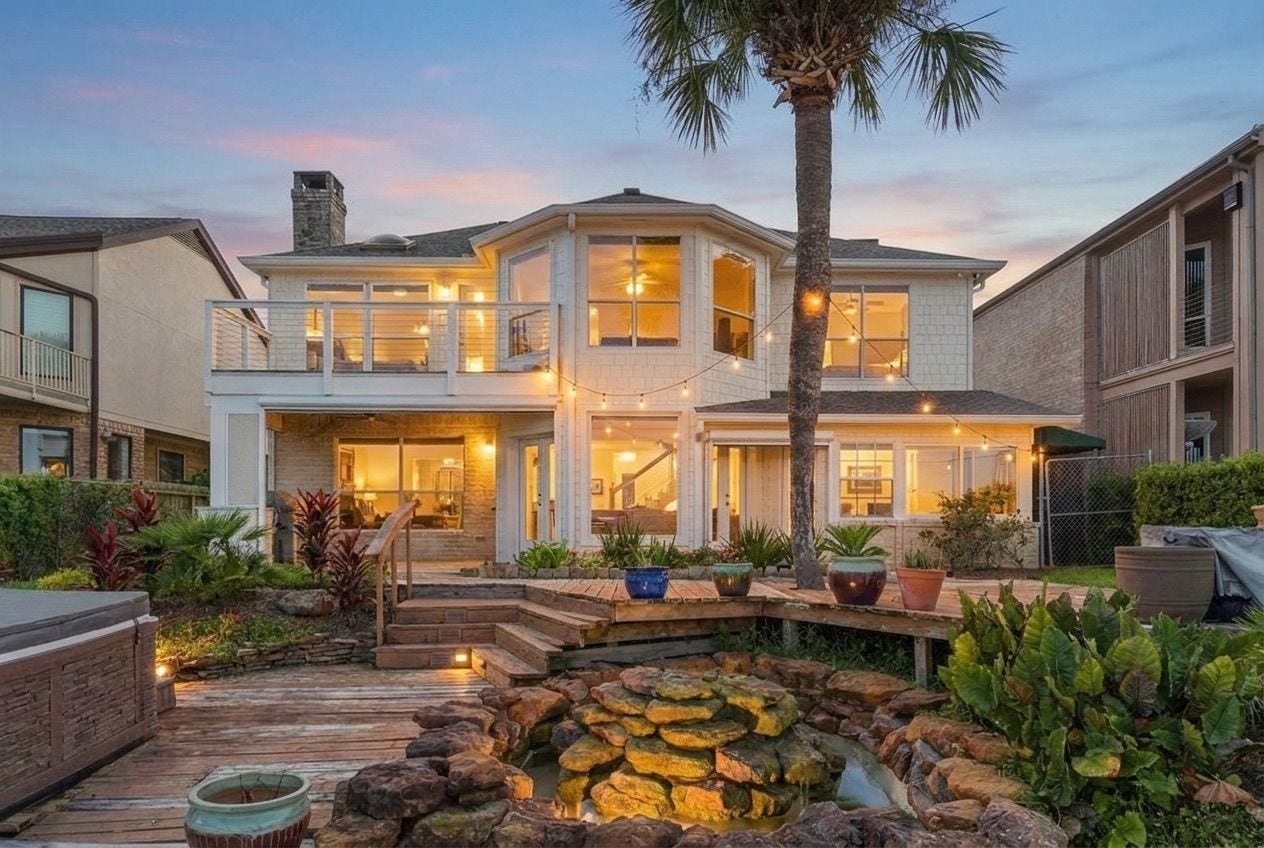 932 Plantation Street, League City, TX 77573 The back of the home features a rock waterfall, lush landscaping, and a private second-floor balcony overlooking the water.