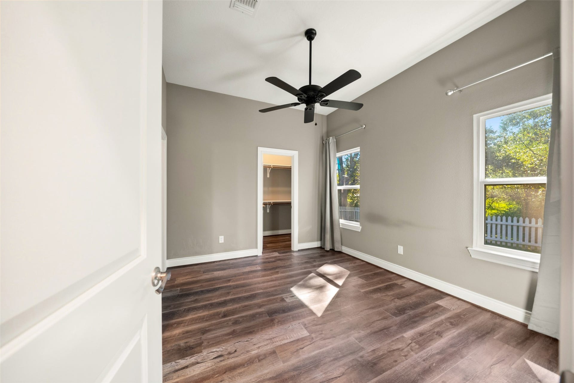 1125 Galveston Street, Hempstead, TX 77445 Bedroom featuring wood-look flooring, a ceiling fan, neutral walls, and natural light from two windows.