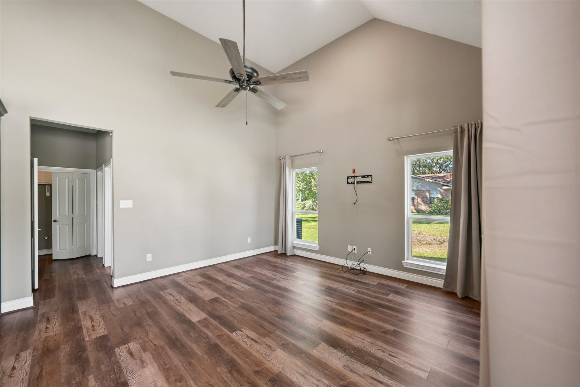 1125 Galveston Street, Hempstead, TX 77445 Living area featuring a vaulted ceiling, ceiling fan, wood-look flooring, and multiple windows for natural light.