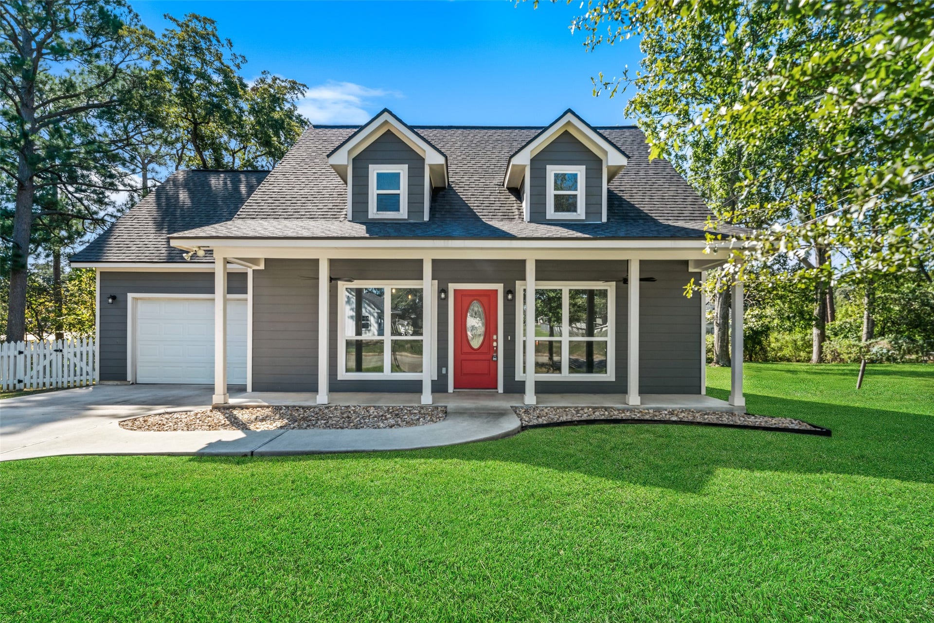 1125 Galveston Street, Hempstead, TX 77445 Front exterior featuring an attached garage, covered porch with white columns, and a spacious lawn.