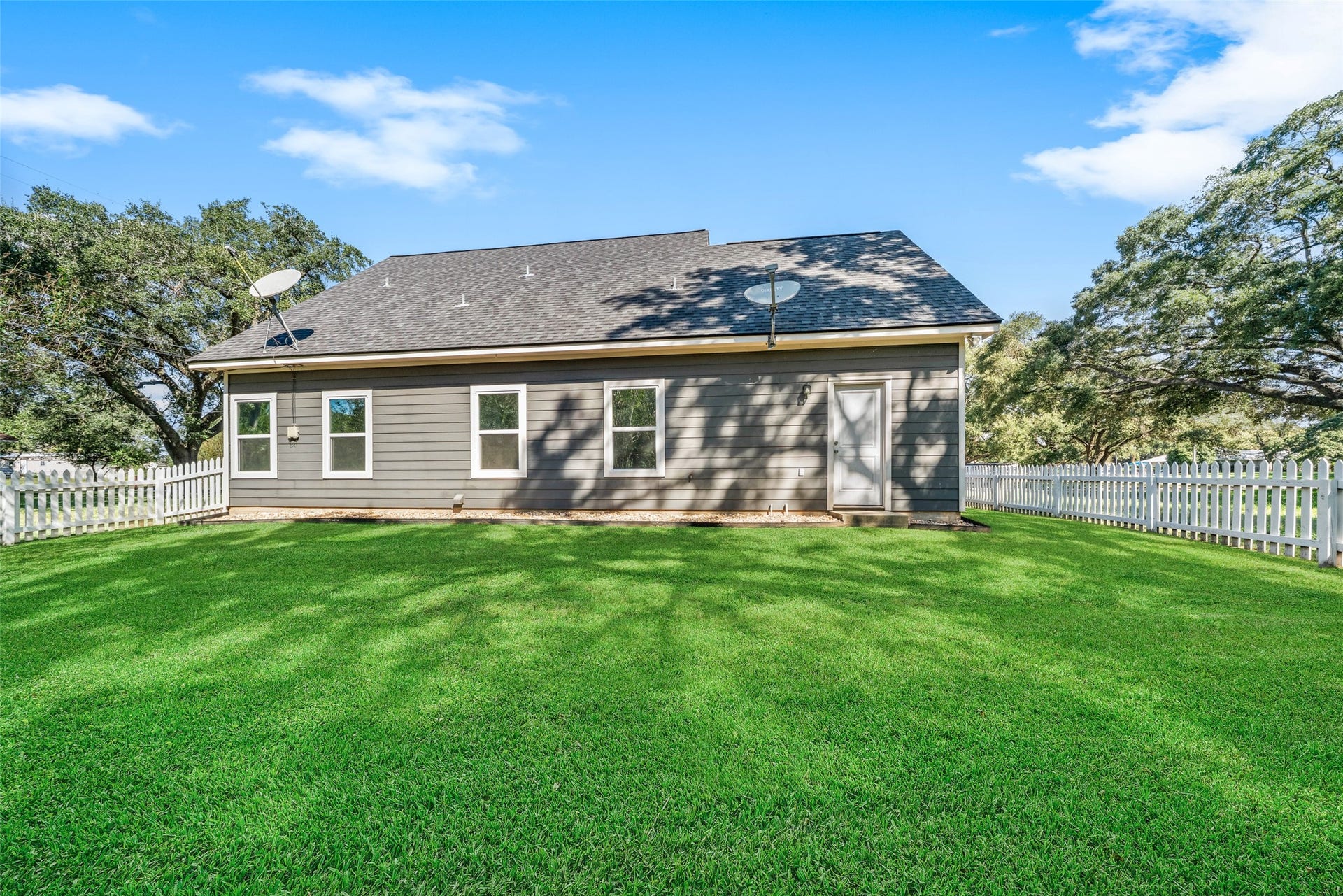 1125 Galveston Street, Hempstead, TX 77445 1. Backyard view featuring the homes stone exterior, spacious lawn, and mature shade trees.