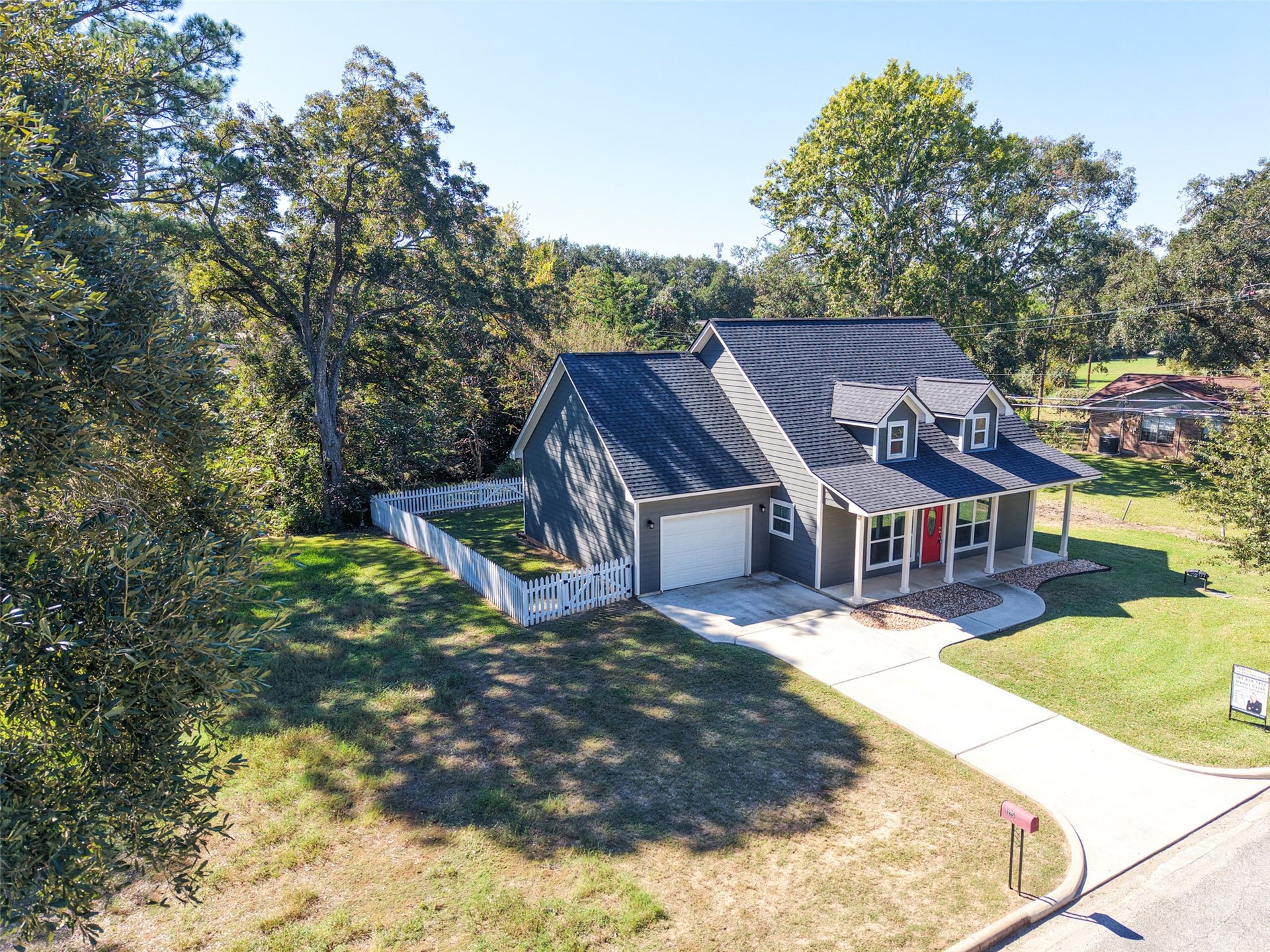 1125 Galveston Street, Hempstead, TX 77445 Elevated front view showcasing the covered porch, attached garage, concrete driveway, and mature shade trees.