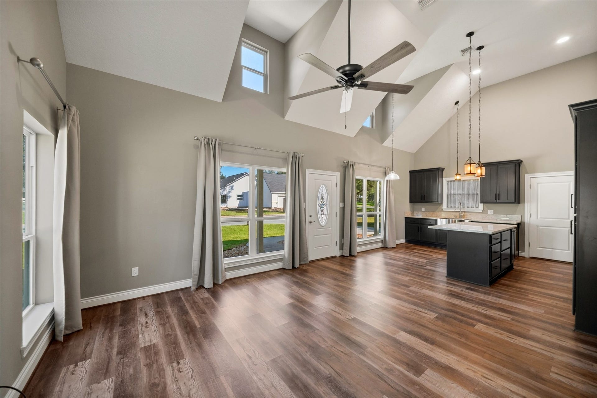 1125 Galveston Street, Hempstead, TX 77445 Spacious living area featuring a vaulted ceiling, upper accent windows, and an adjoining island kitchen.