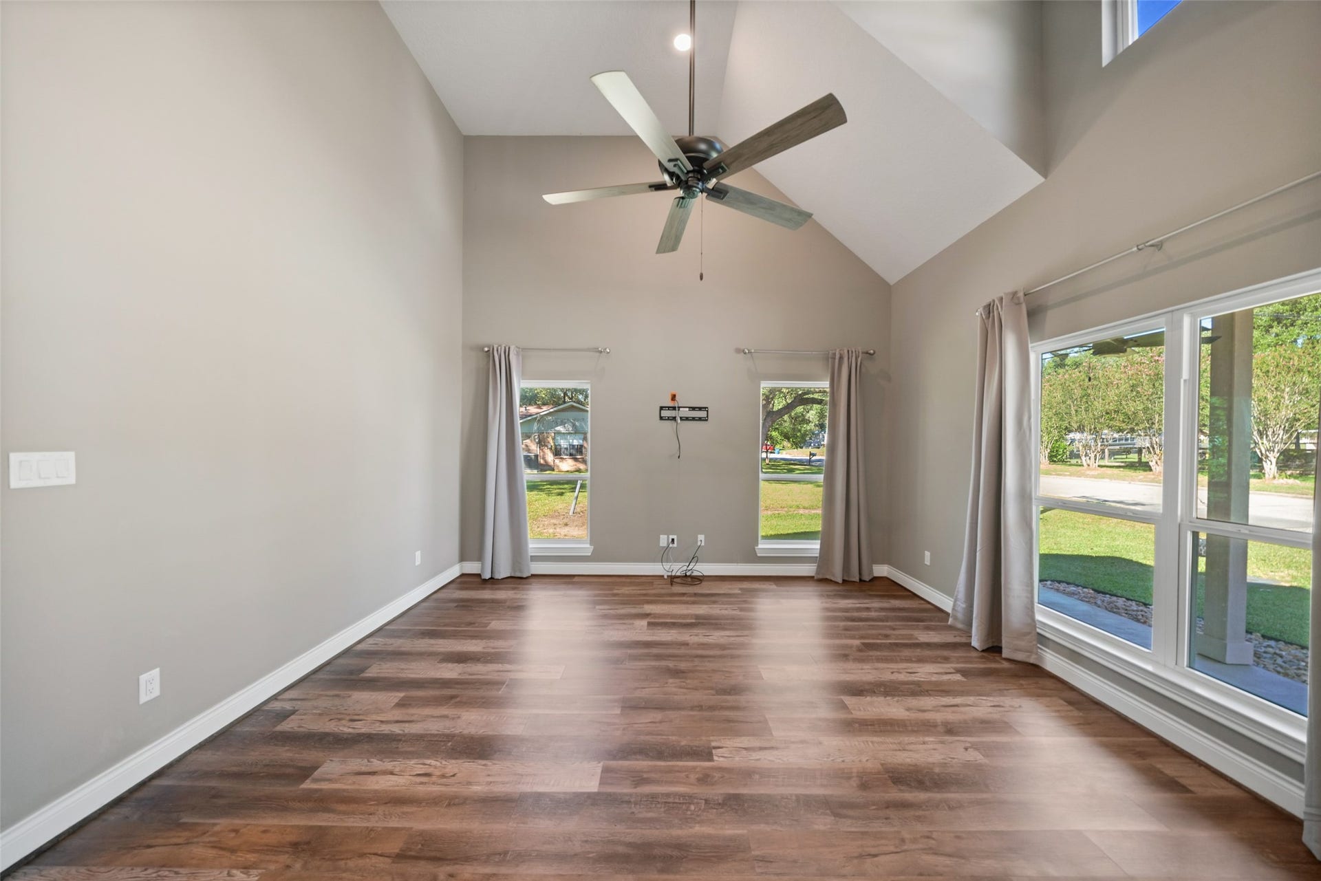 1125 Galveston Street, Hempstead, TX 77445 Living area featuring a vaulted ceiling, upper accent windows, and large windows with views of the fenced yard.