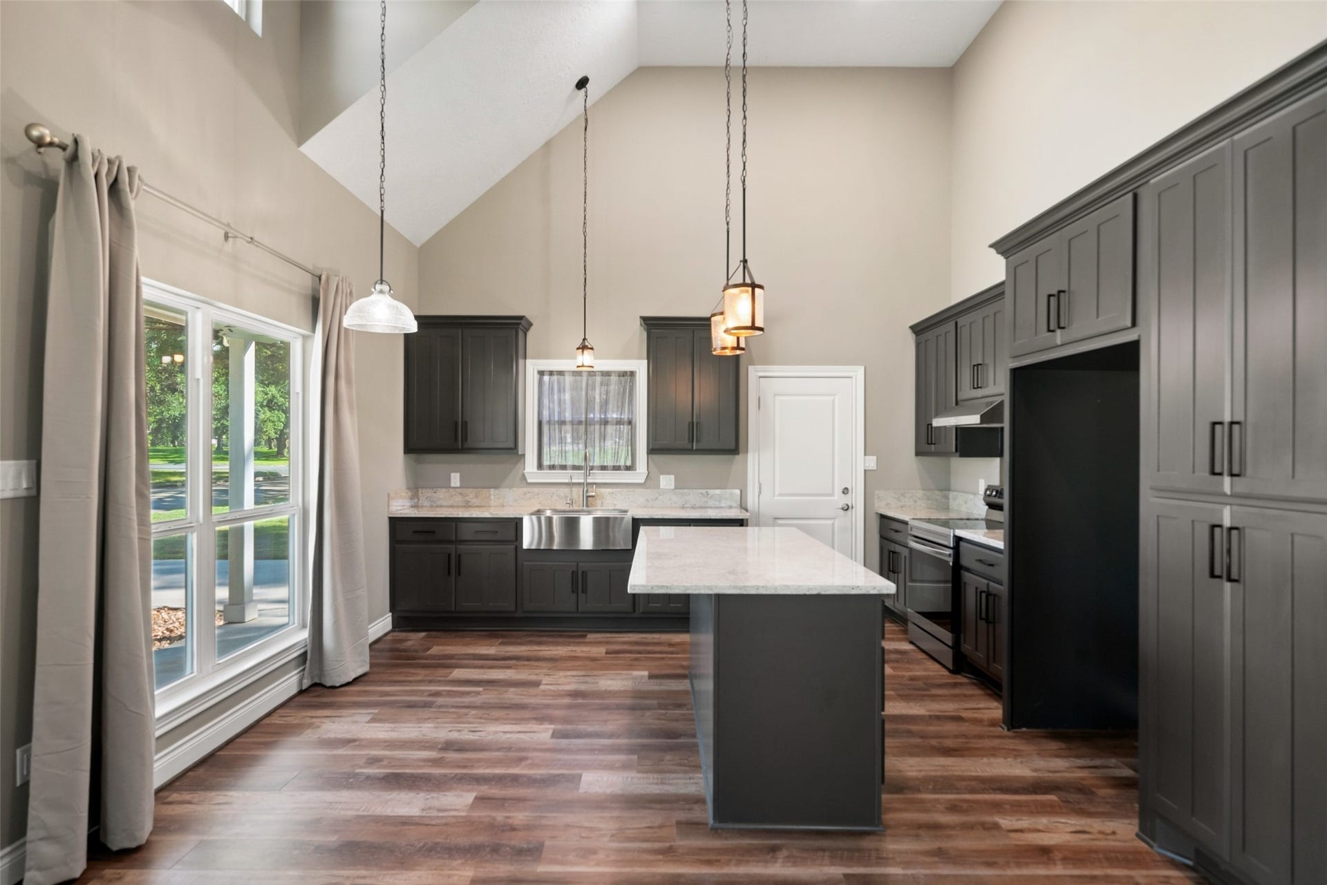 1125 Galveston Street, Hempstead, TX 77445 Kitchen featuring dark cabinetry, a center island, pendant lighting, and a stainless steel apron-front sink beneath the window.